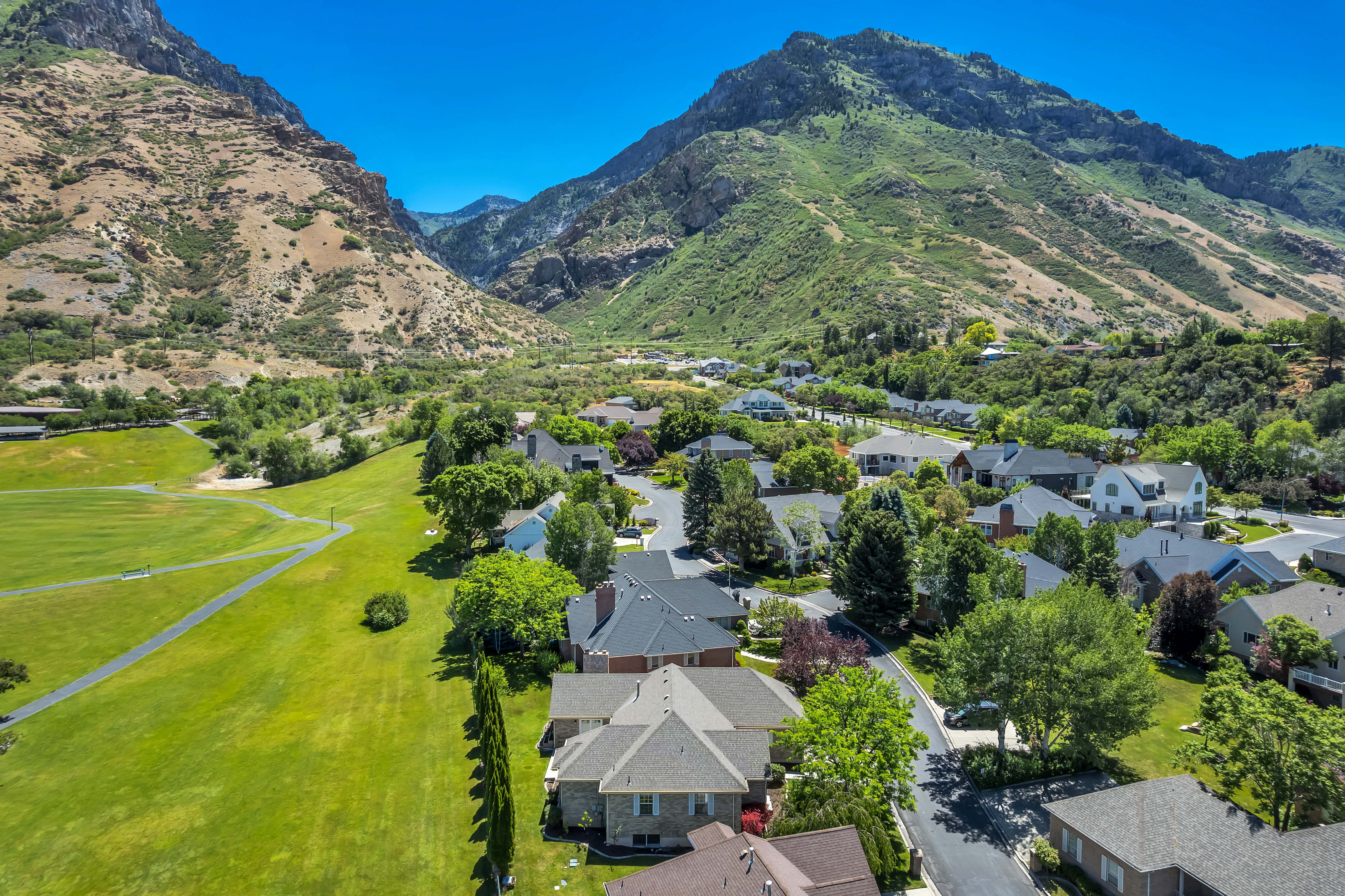 Residential community nestled at the base of verdant mountains, featuring established homes with varied architectural styles and mature landscaping