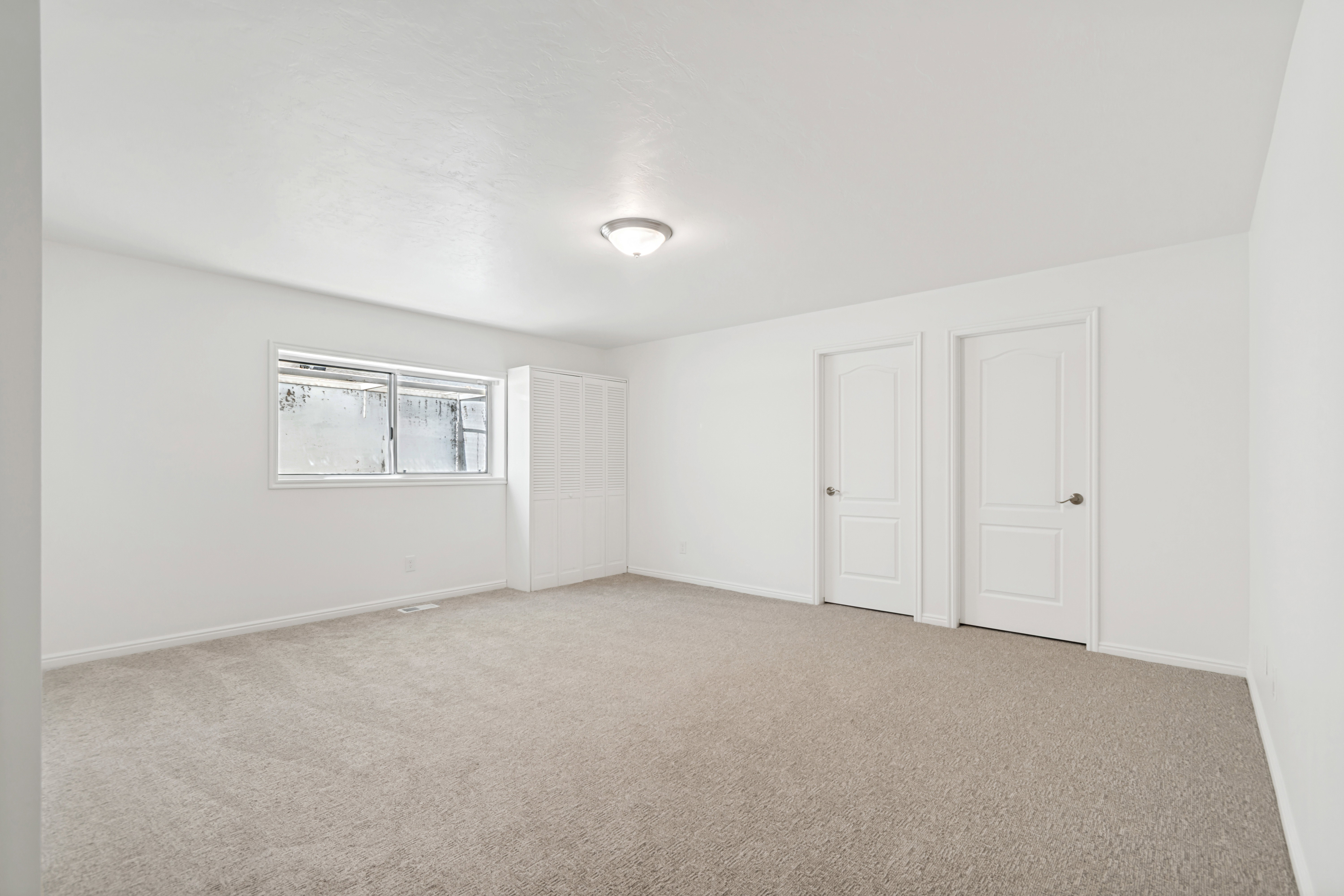 Spacious room featuring neutral carpet flooring and white painted walls