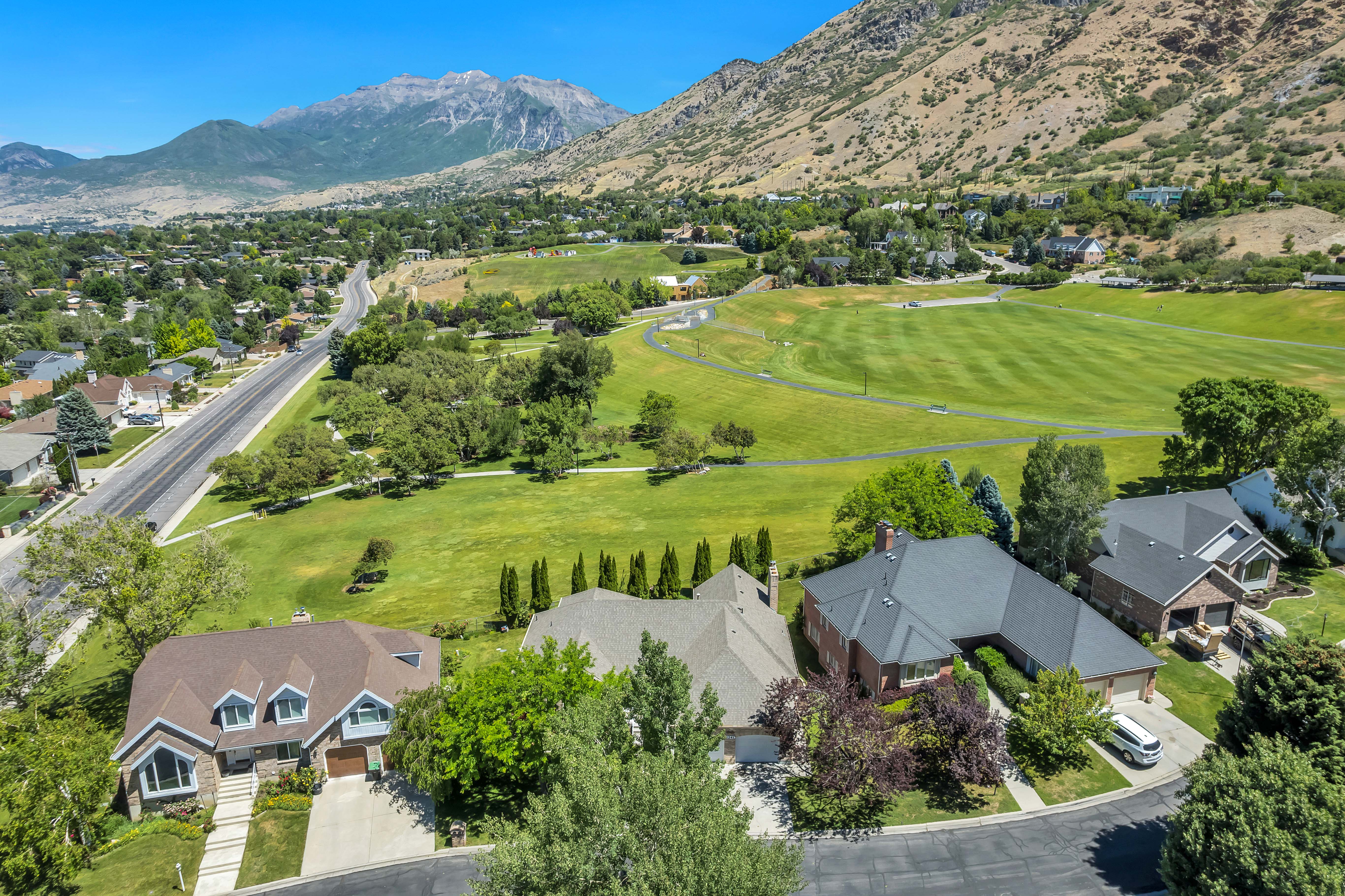 Aerial perspective showcasing the residential street with a backdrop of mountains and open green spaces