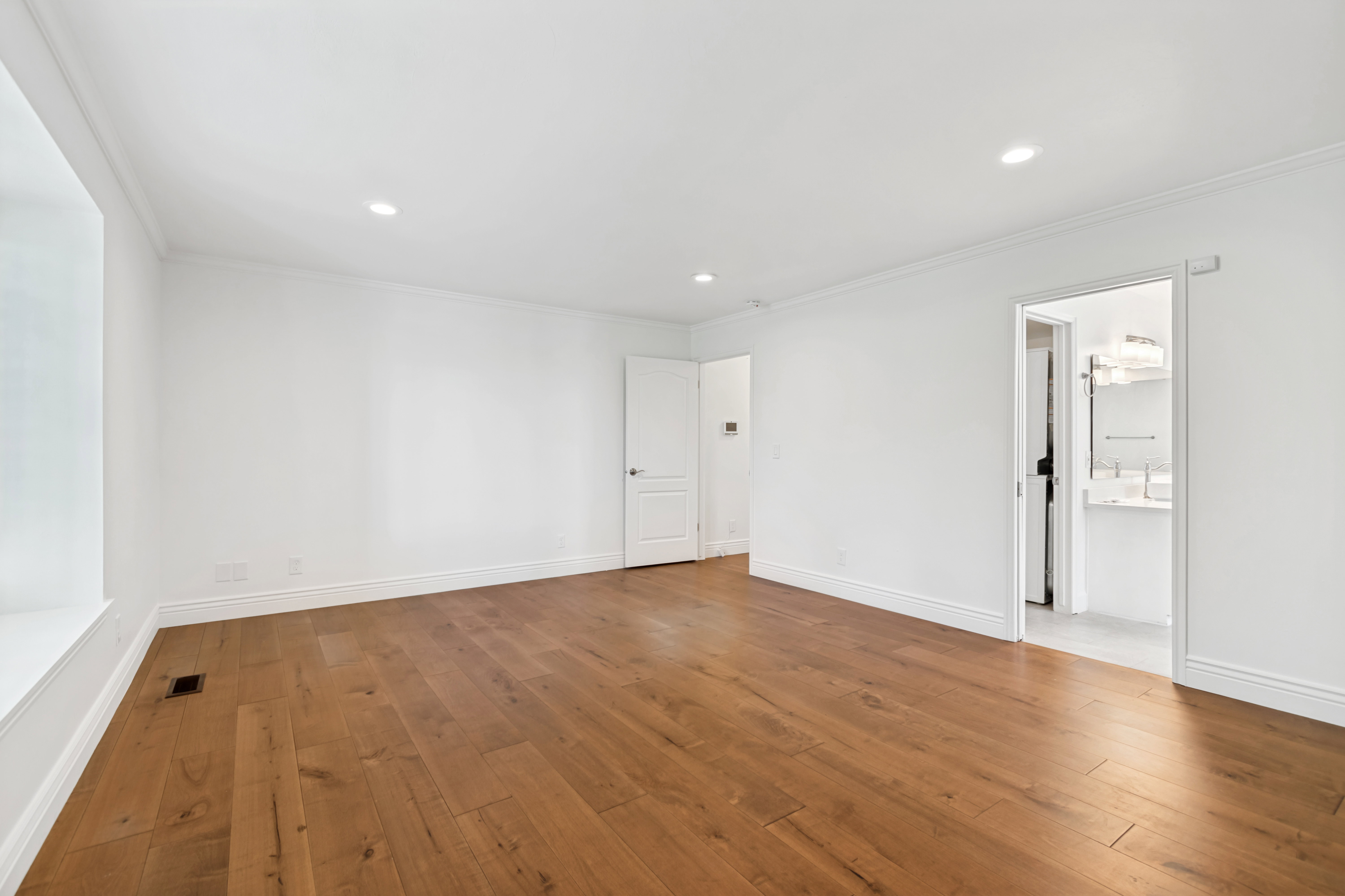 Spacious room featuring wood-finish flooring, white walls, and recessed lighting