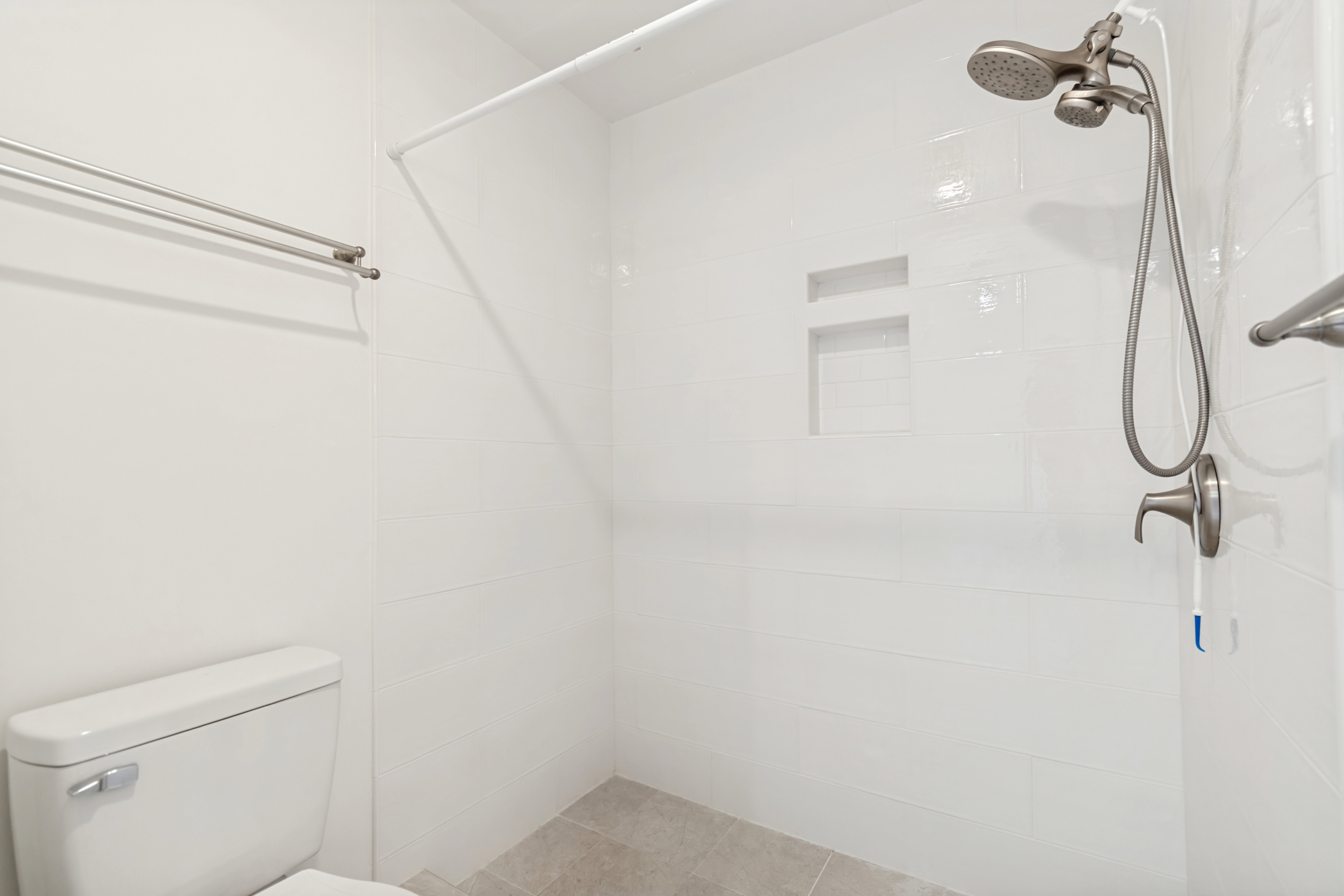 White subway tile shower surround with dual recessed niches and brushed nickel fixtures