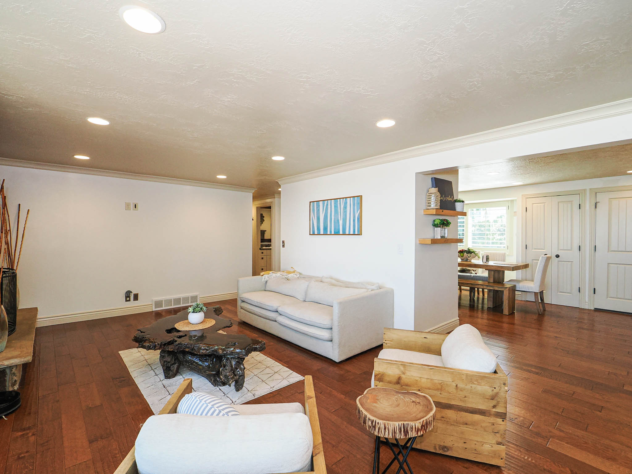 Living area featuring wood-finish flooring, recessed lighting, white crown molding, and a wide entryway to an adjacent dining space