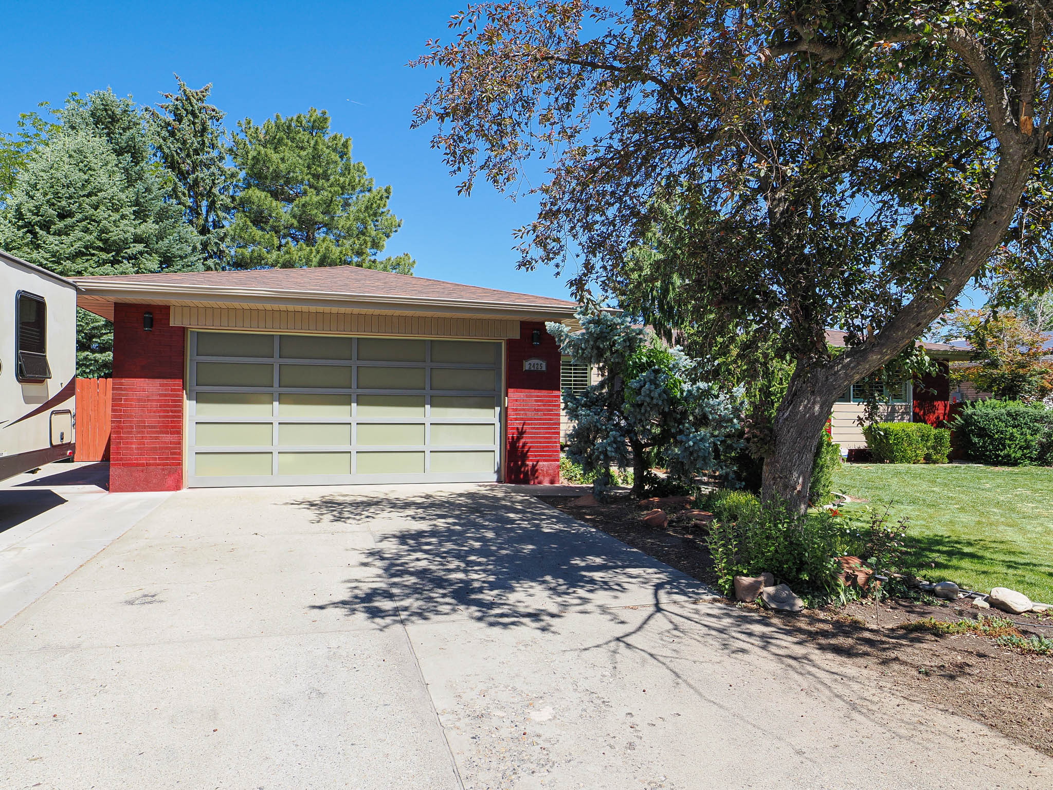 Red brick facade with a contemporary garage door and concrete driveway
