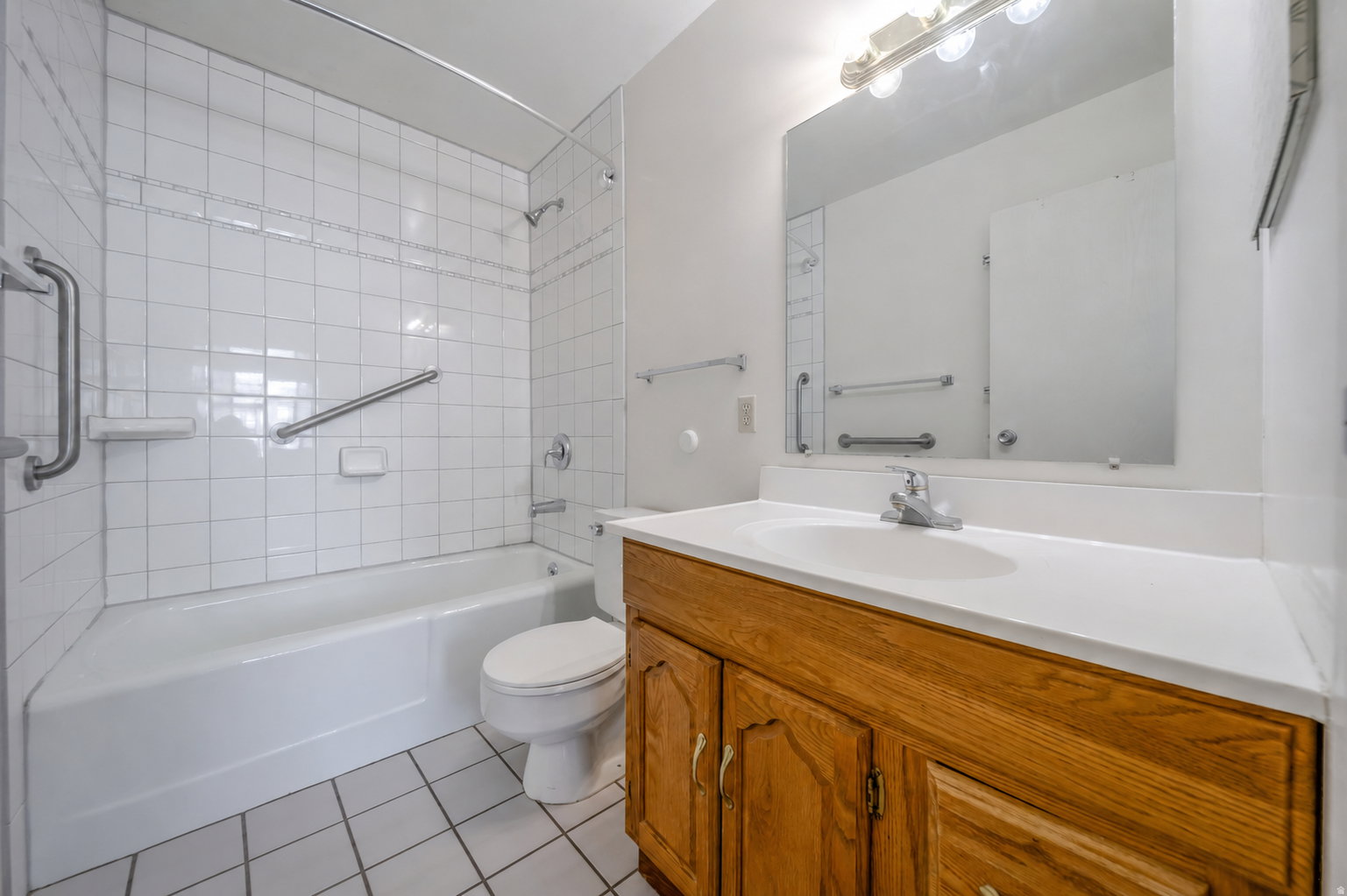 Bathroom featuring a white subway tile tub surround, white bathtub, and grab bars