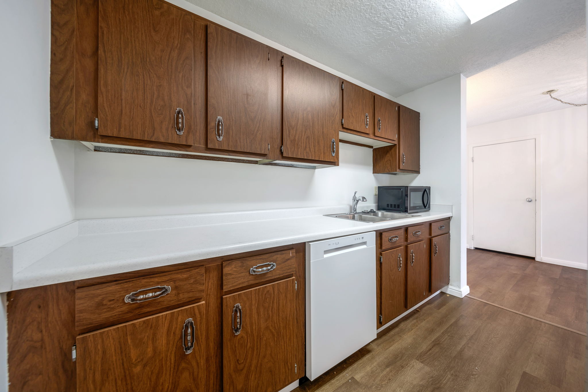 Kitchen featuring wood-finish cabinetry, white countertops, and a stainless steel sink with a chrome faucet