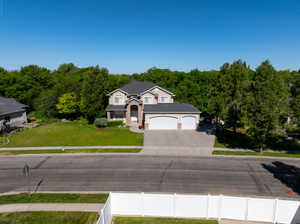 Two-story residence featuring a stone and stucco exterior, a dark shingle roof, and a three-car garage