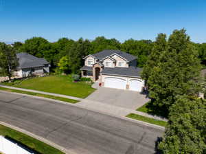 Two-story property featuring a tan stucco and brick facade with a prominent two-car garage