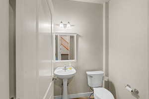 Pedestal sink with chrome fixtures, white framed mirror, and a wall-mounted light fixture with frosted glass shades
