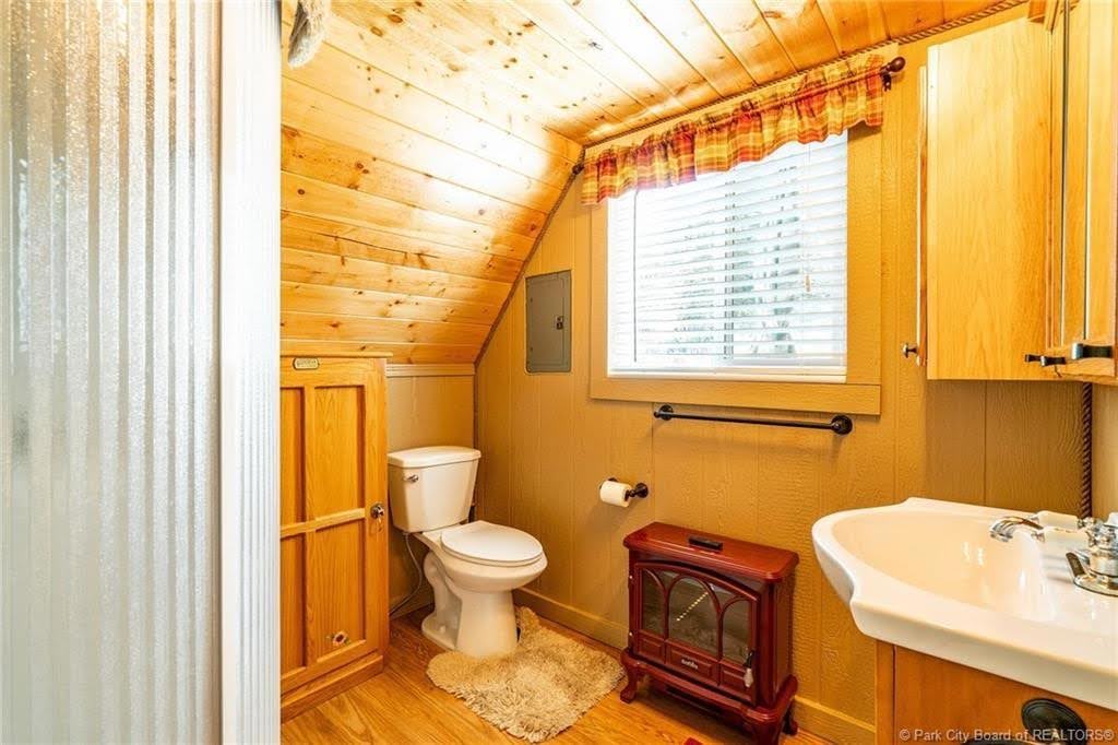 Compact bathroom featuring wood-finish flooring, a white toilet, and a stand-alone sink with a vanity cabinet