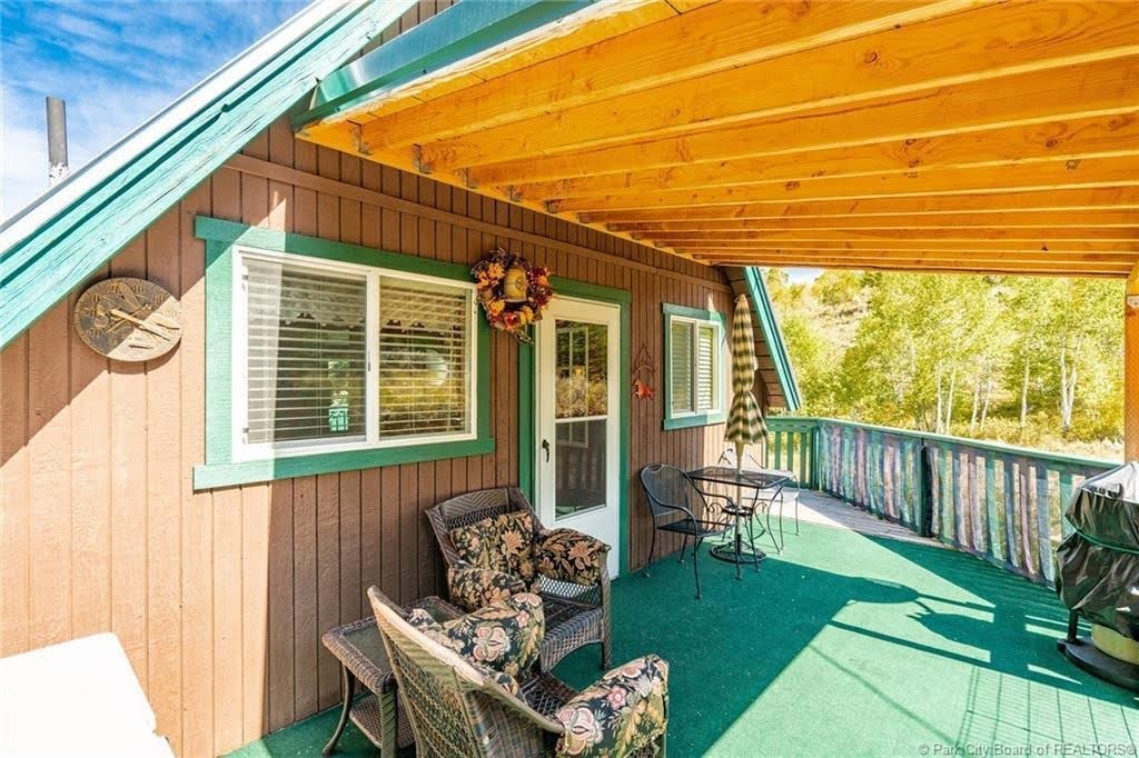 Covered exterior deck with green surface, wood plank siding, and a wood slat ceiling