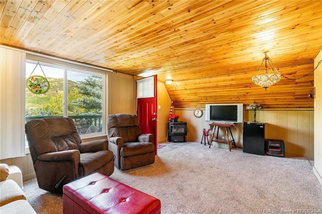 Room featuring a wood-panel ceiling, light-colored carpet, and a large window offering expansive scenery