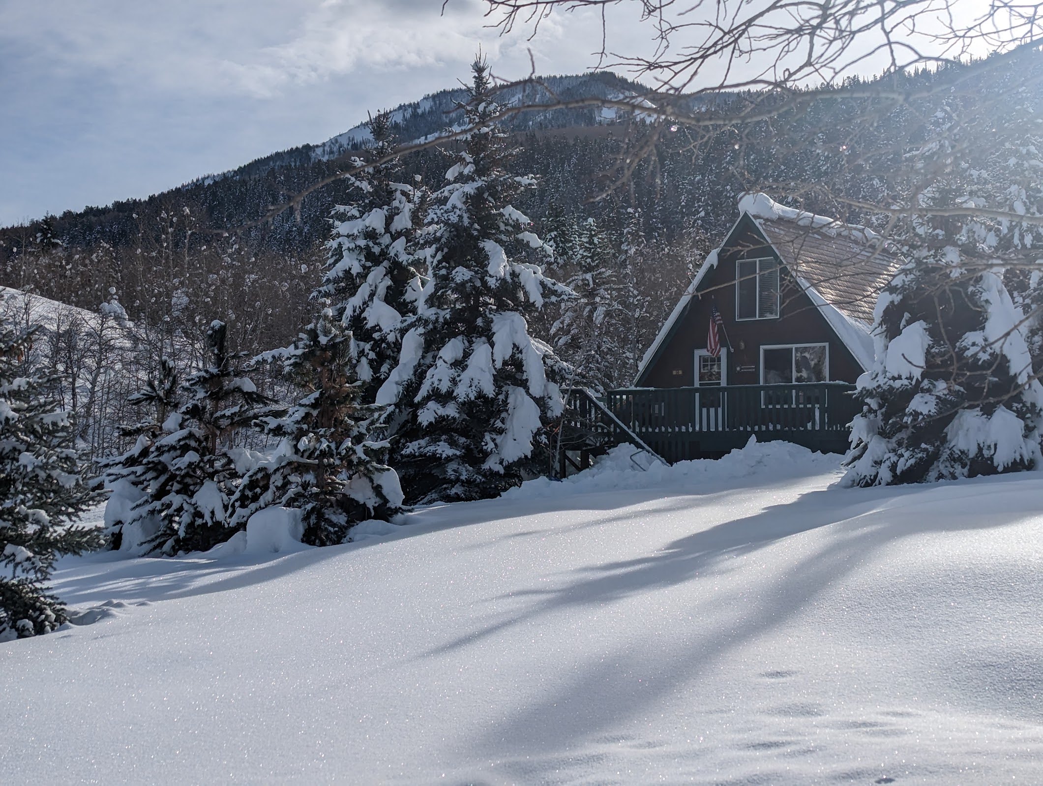 A-frame residence featuring a dark exterior, a prominent wooden deck, and a classic A-frame roofline