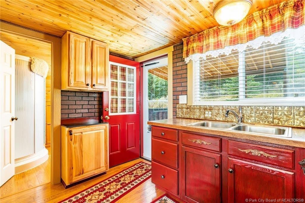 Kitchen featuring wood-finish flooring and ceiling, red cabinetry, and a double basin stainless steel sink