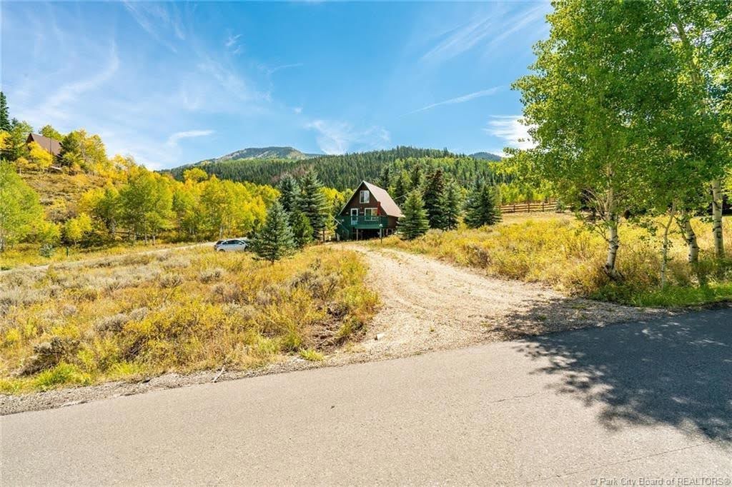 A-frame style residence surrounded by mature evergreen trees and deciduous foliage with yellow leaves