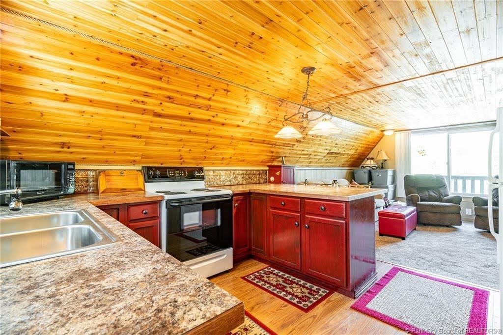Kitchen area featuring a wood-panel sloped ceiling and wood-finish flooring
