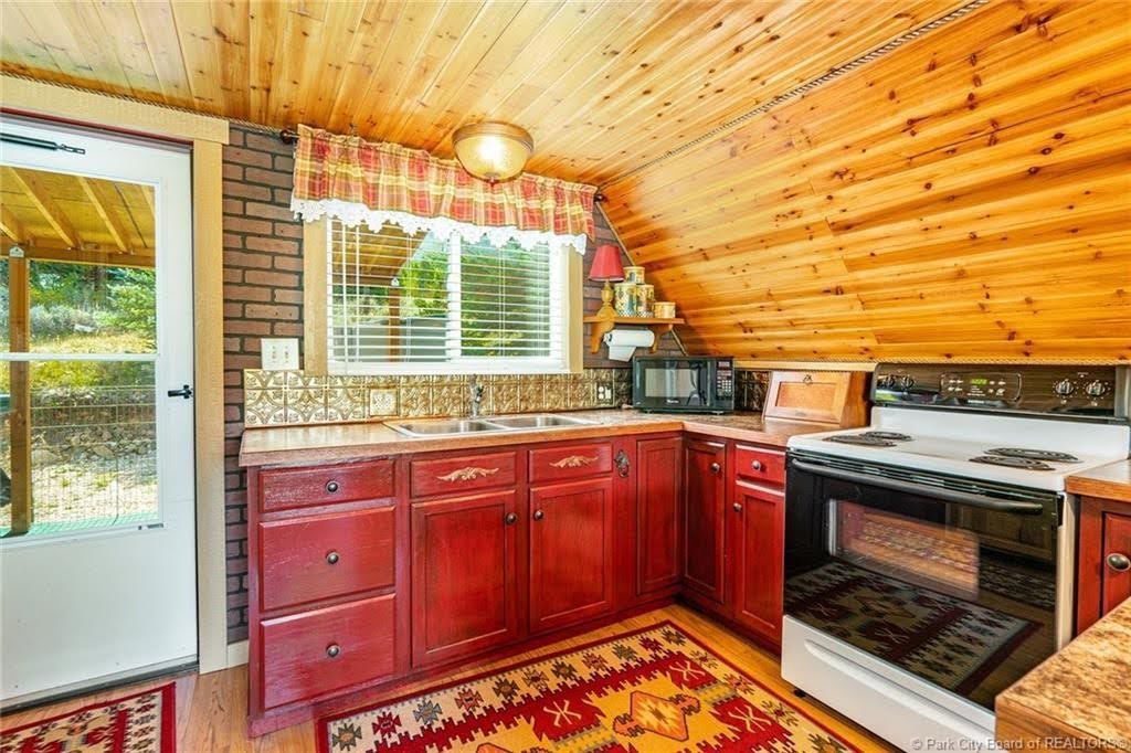 Kitchen featuring red cabinetry, a white electric range, and a double basin sink