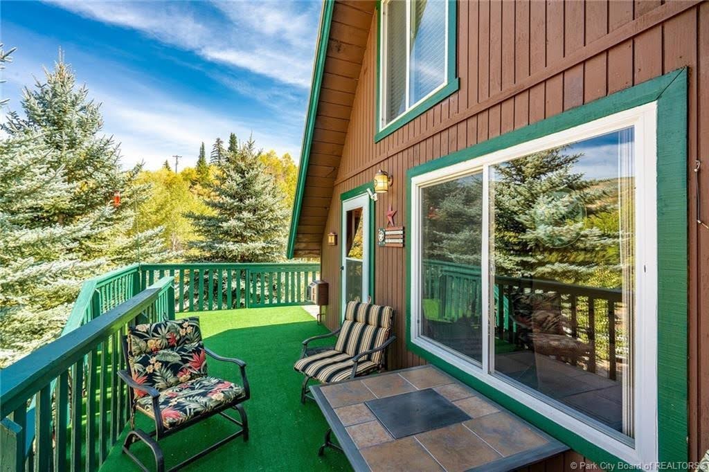 Outdoor deck with green railing, featuring a faux turf surface