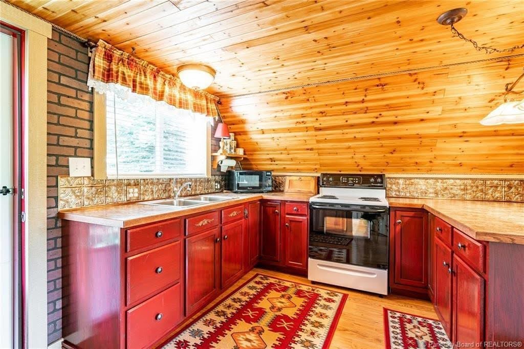 Kitchen featuring wood-finish flooring, wood plank ceiling, red cabinetry, and a double basin stainless steel sink