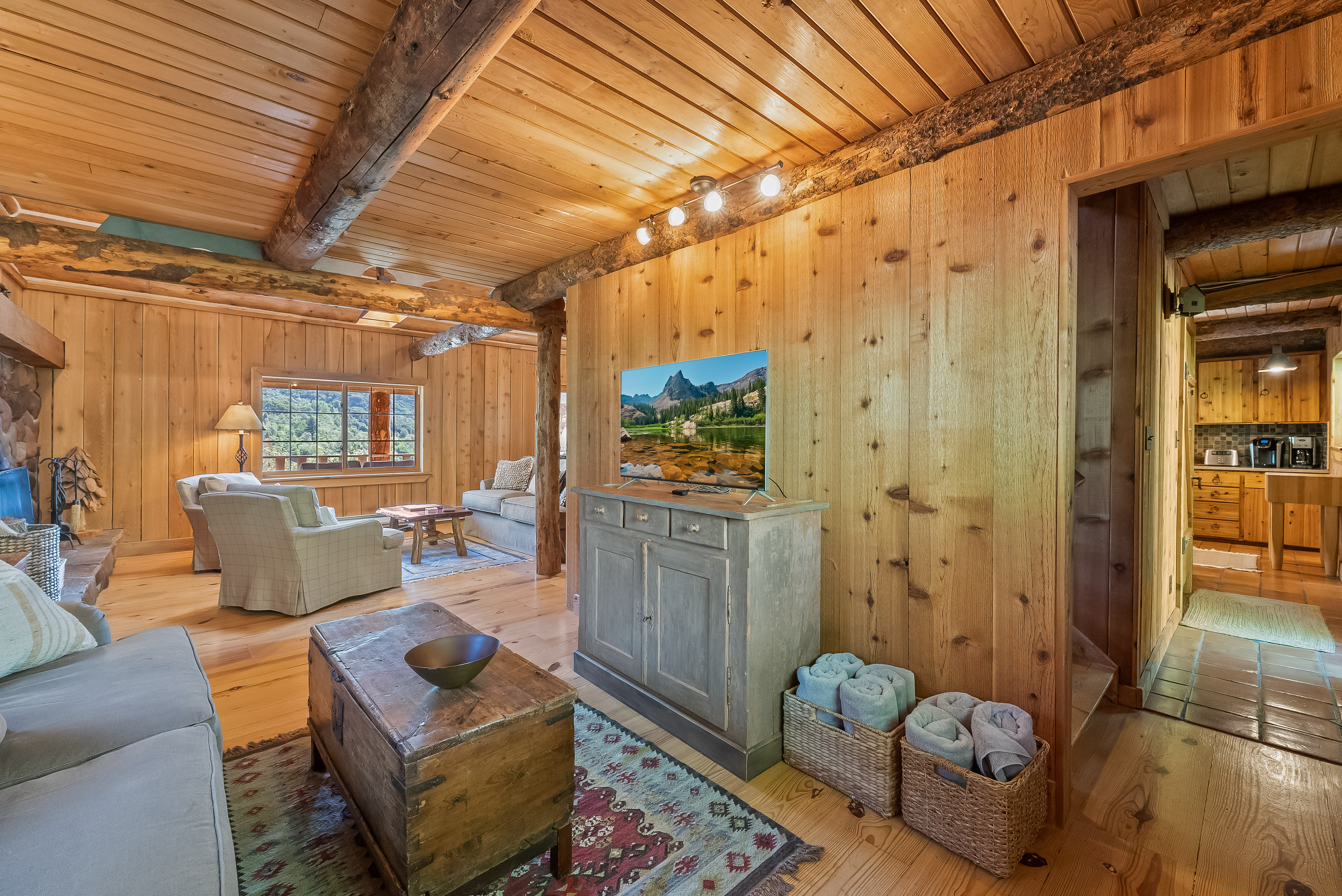 Living area featuring wood-paneled walls and ceilings, exposed wood beams, and light wood-finish flooring