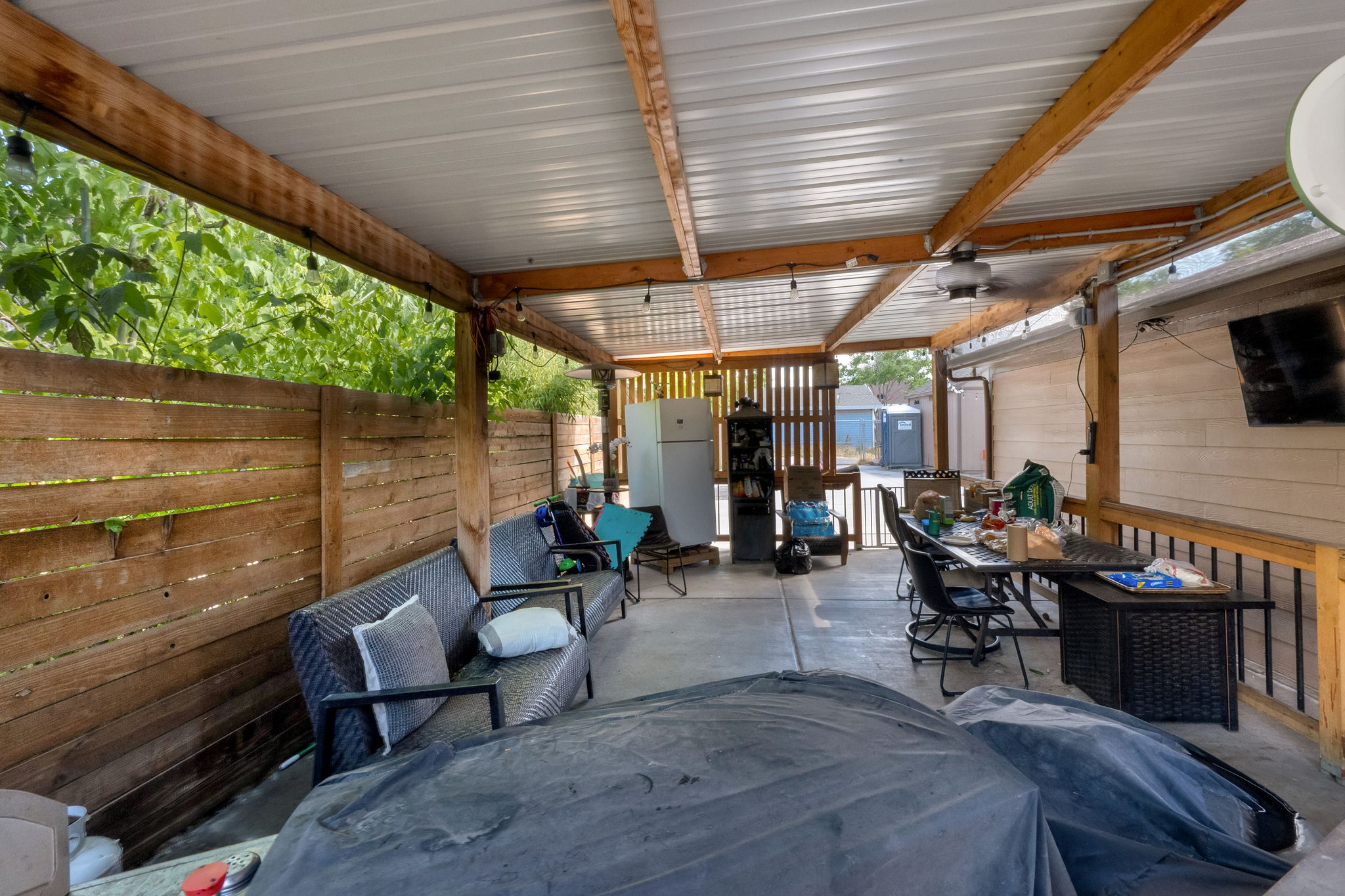 Covered patio featuring a corrugated metal roof supported by exposed timber beams