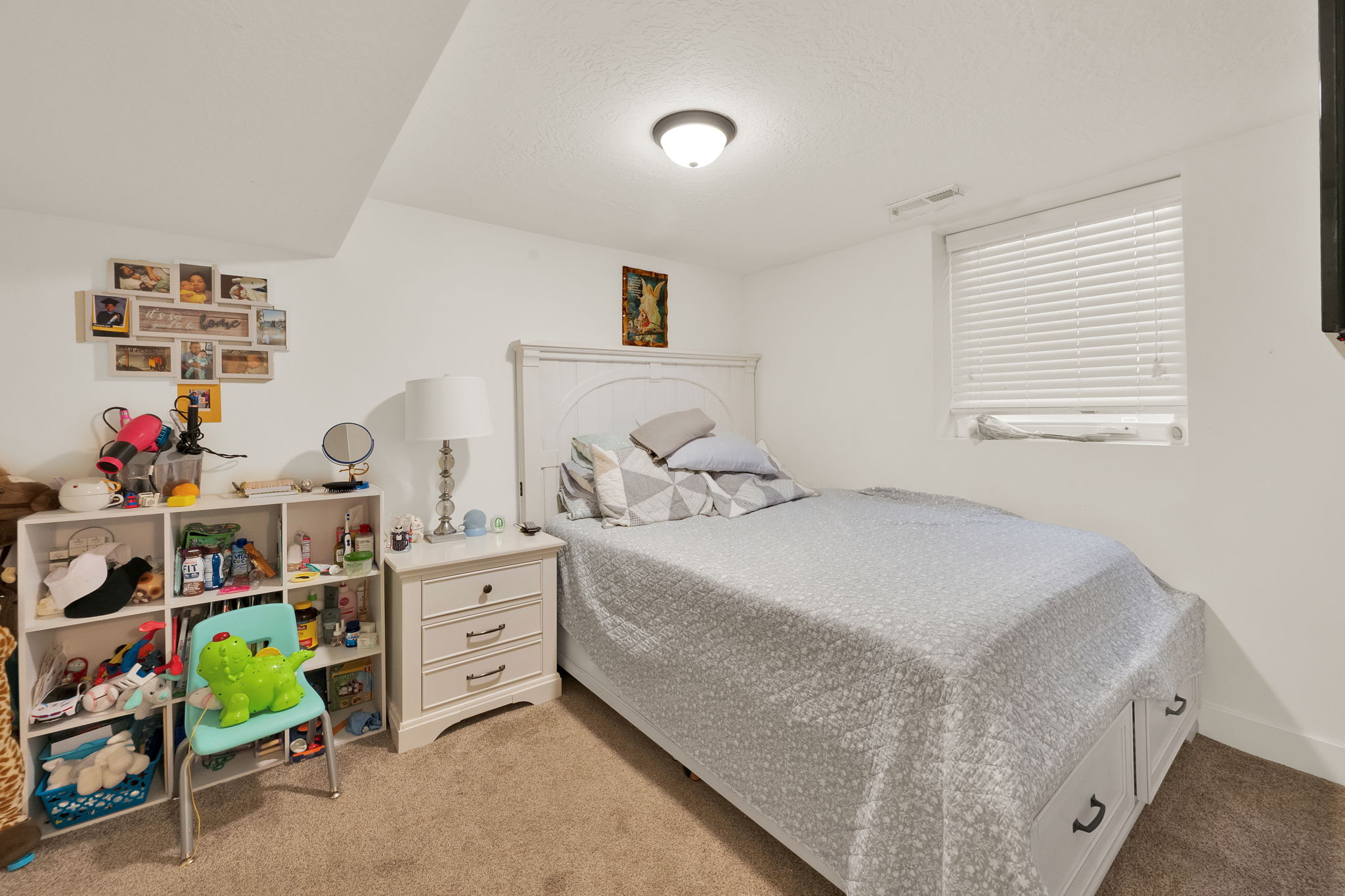 Carpeted bedroom featuring white walls and a window with blinds