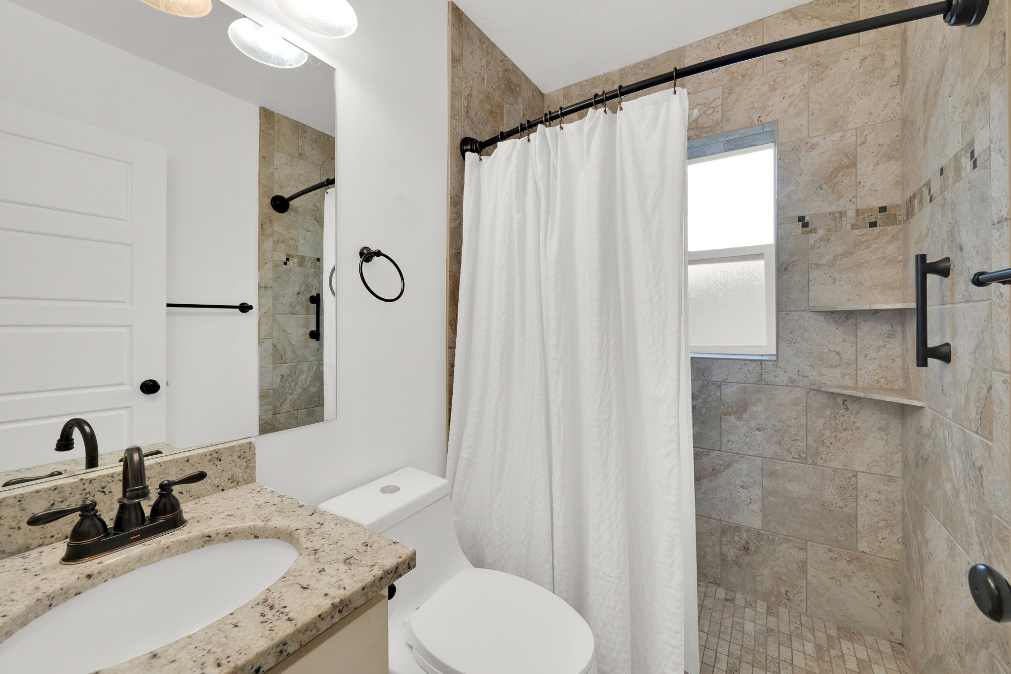 Bathroom featuring a granite countertop vanity with an undermount sink and oil-rubbed bronze fixtures