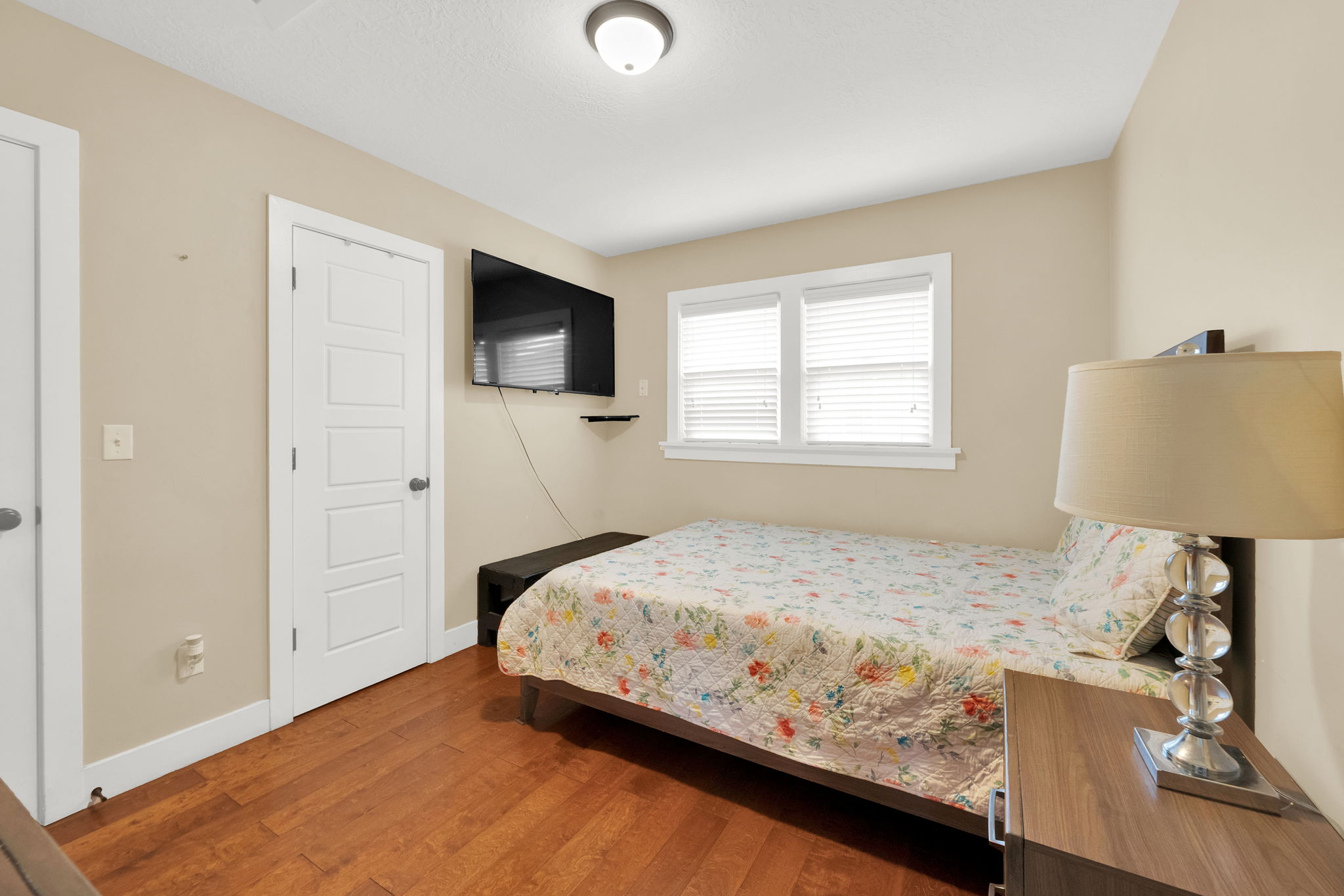 Bedroom featuring warm wood-finish flooring, light neutral-toned walls, and a white ceiling
