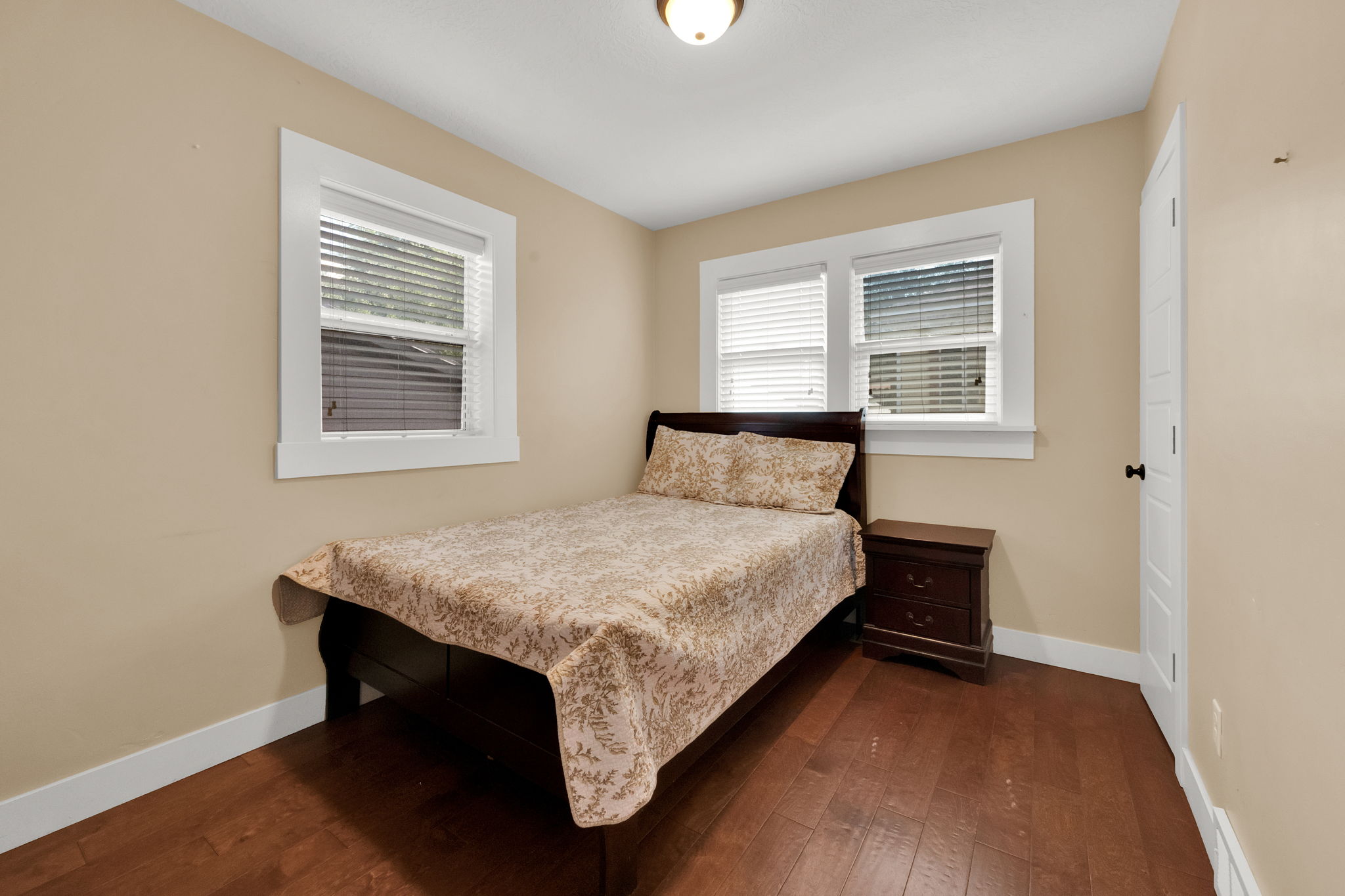 Hardwood-finish flooring, multiple windows with white trim, and a panel-style door with dark hardware
