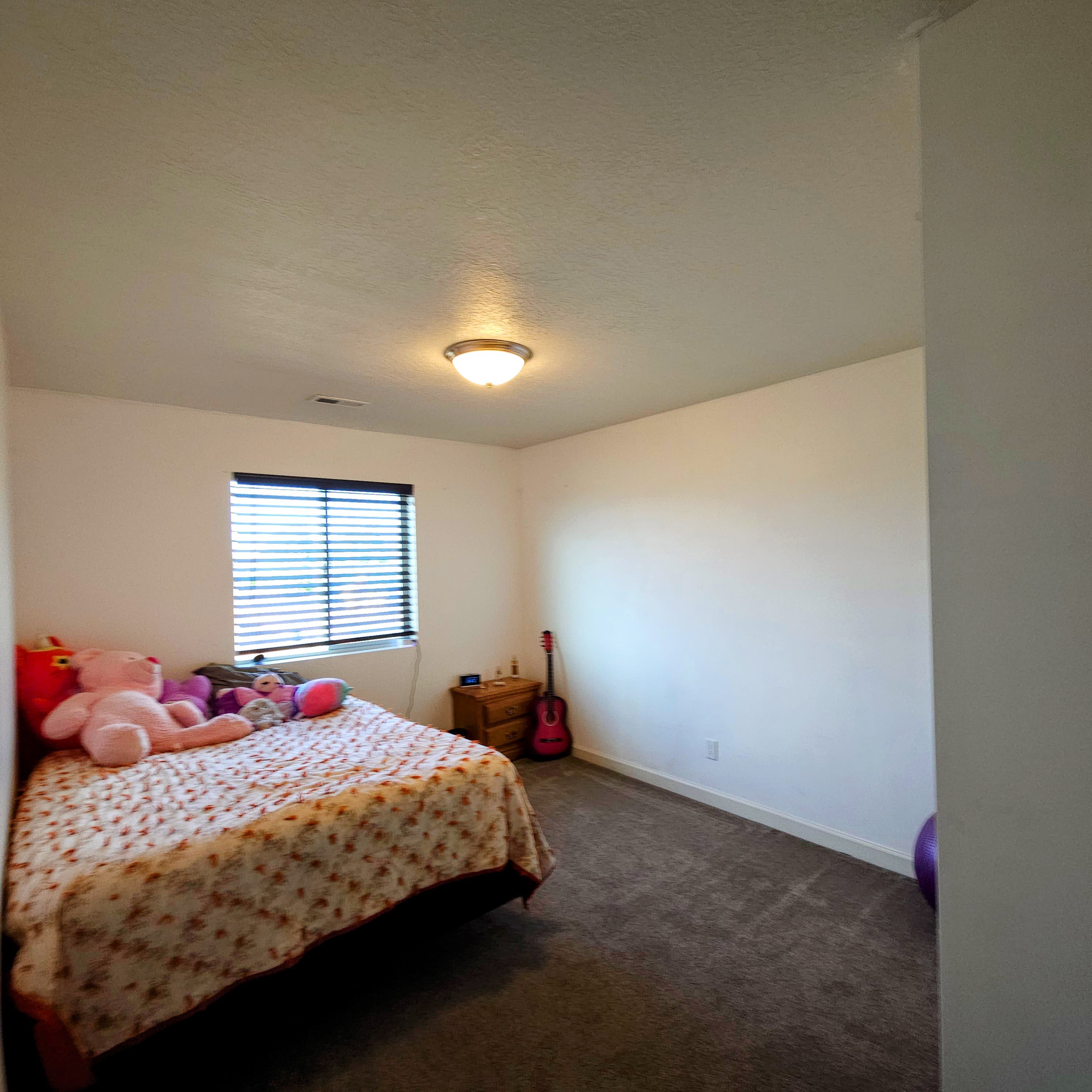 Carpeted room with a window featuring horizontal blinds