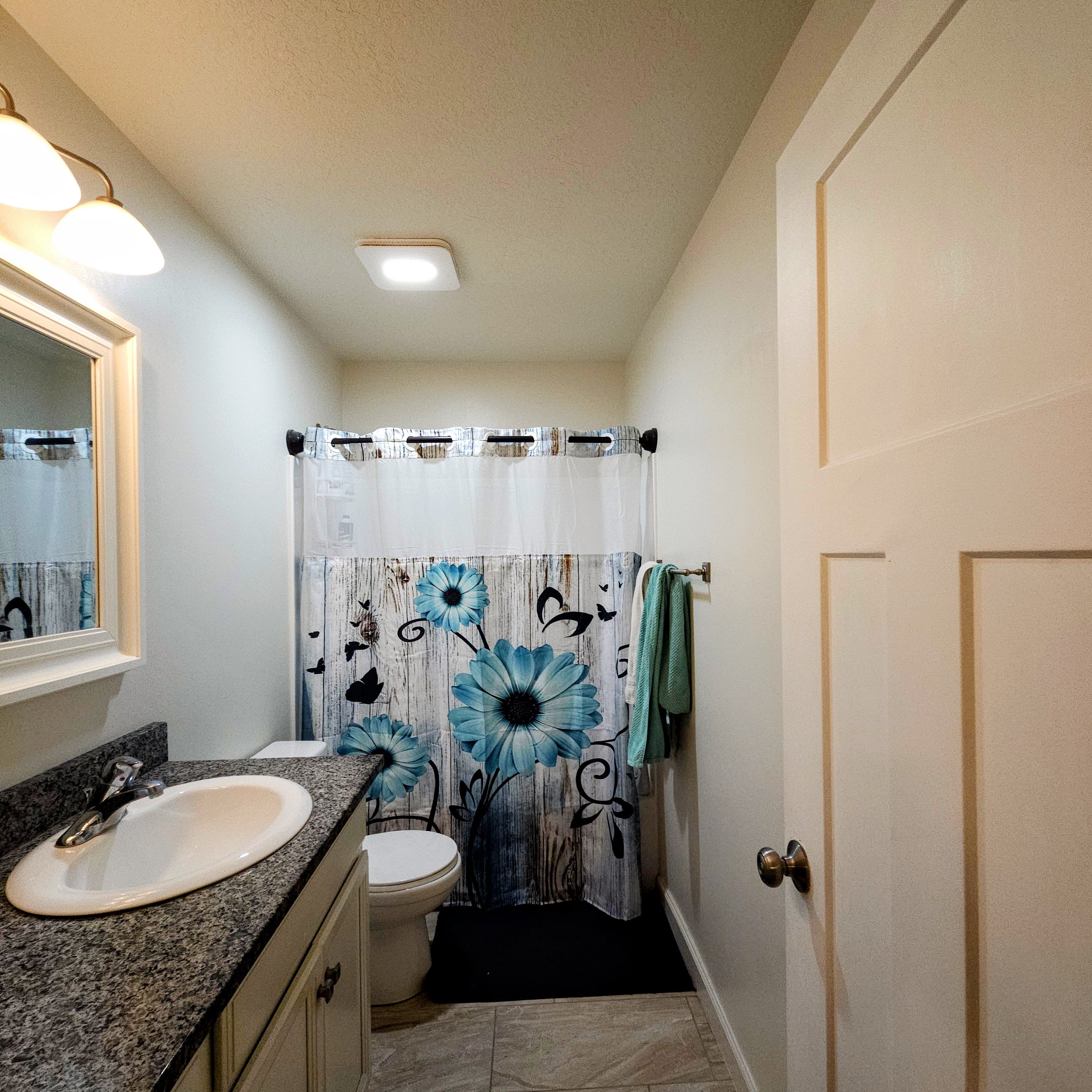 Bathroom featuring a vanity with an integrated sink, a dark speckled countertop, and light-toned cabinetry