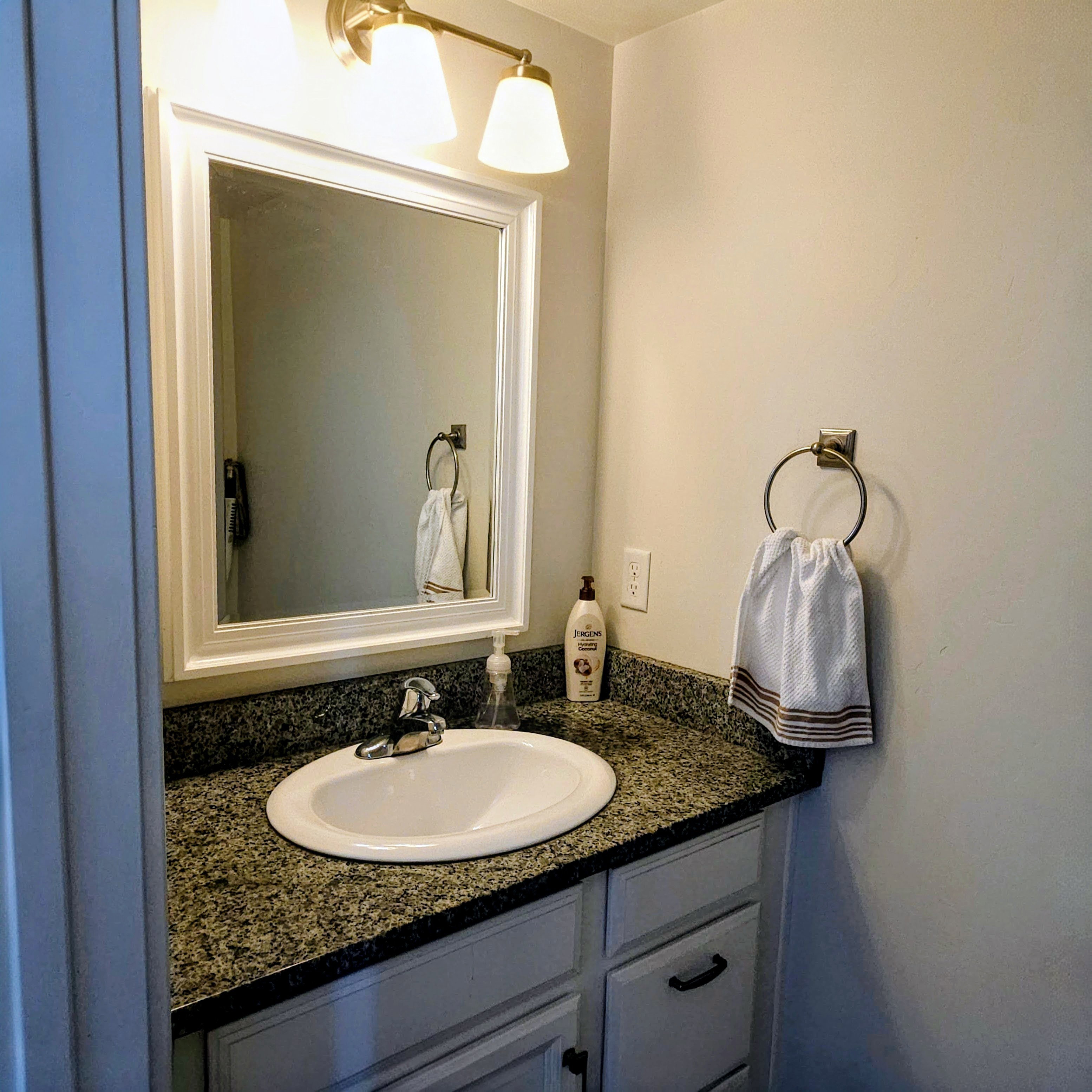 Vanity featuring an integrated sink, speckled countertop, and white cabinetry with dark hardware