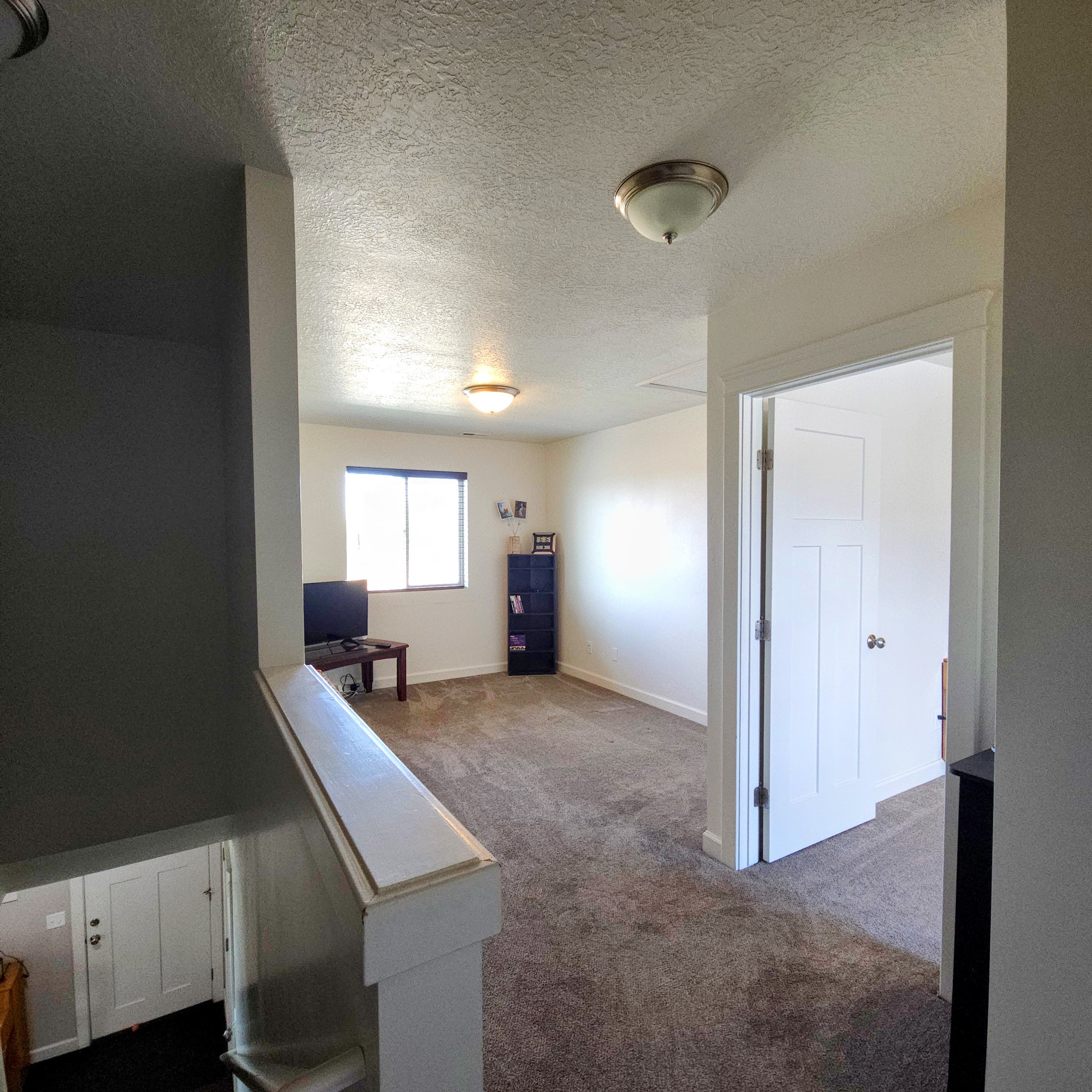 Carpeted upper-level landing featuring a broad window, white trim, and a flush mount light fixture