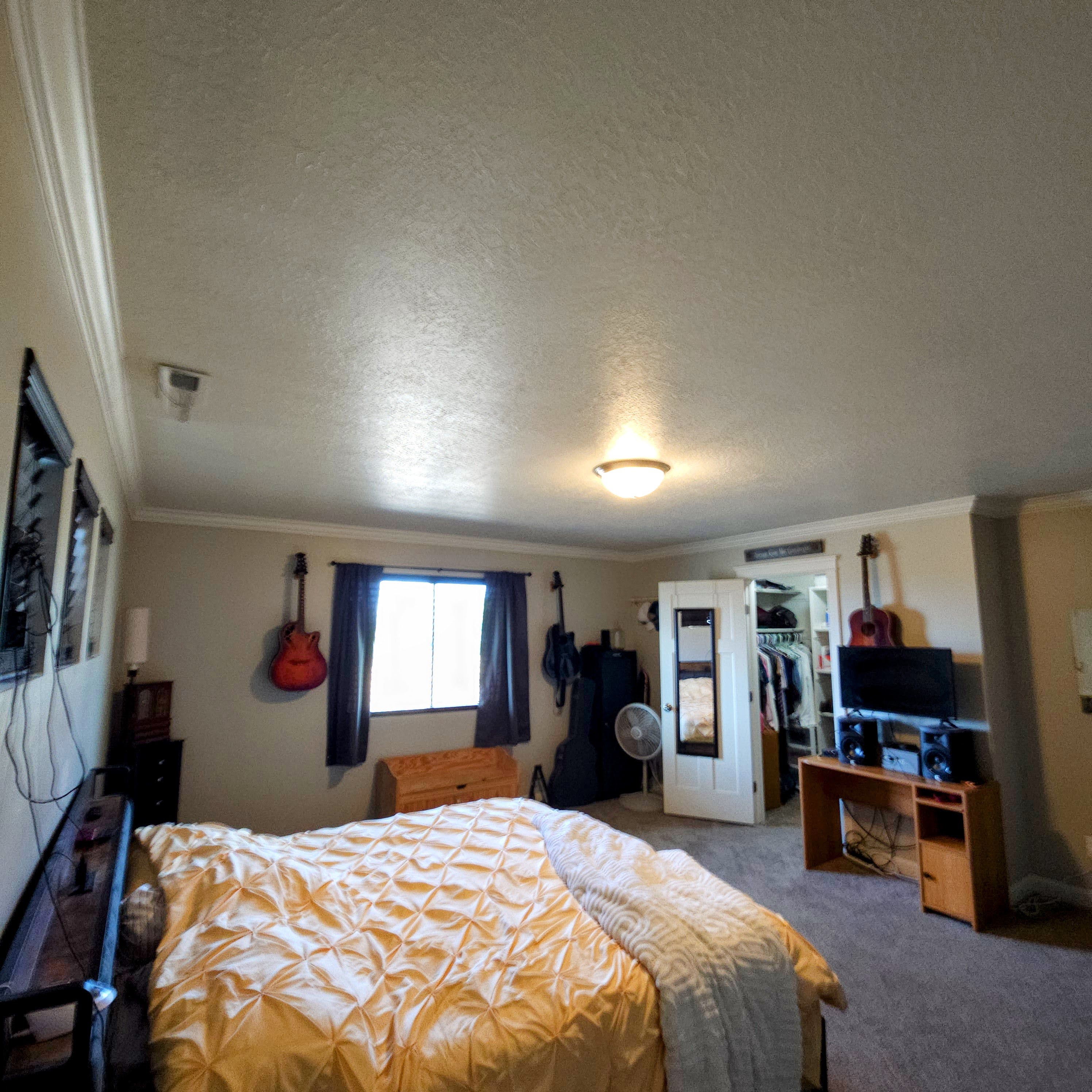 Spacious room featuring a central window with dark drapes, crown molding, and a flush mount ceiling light