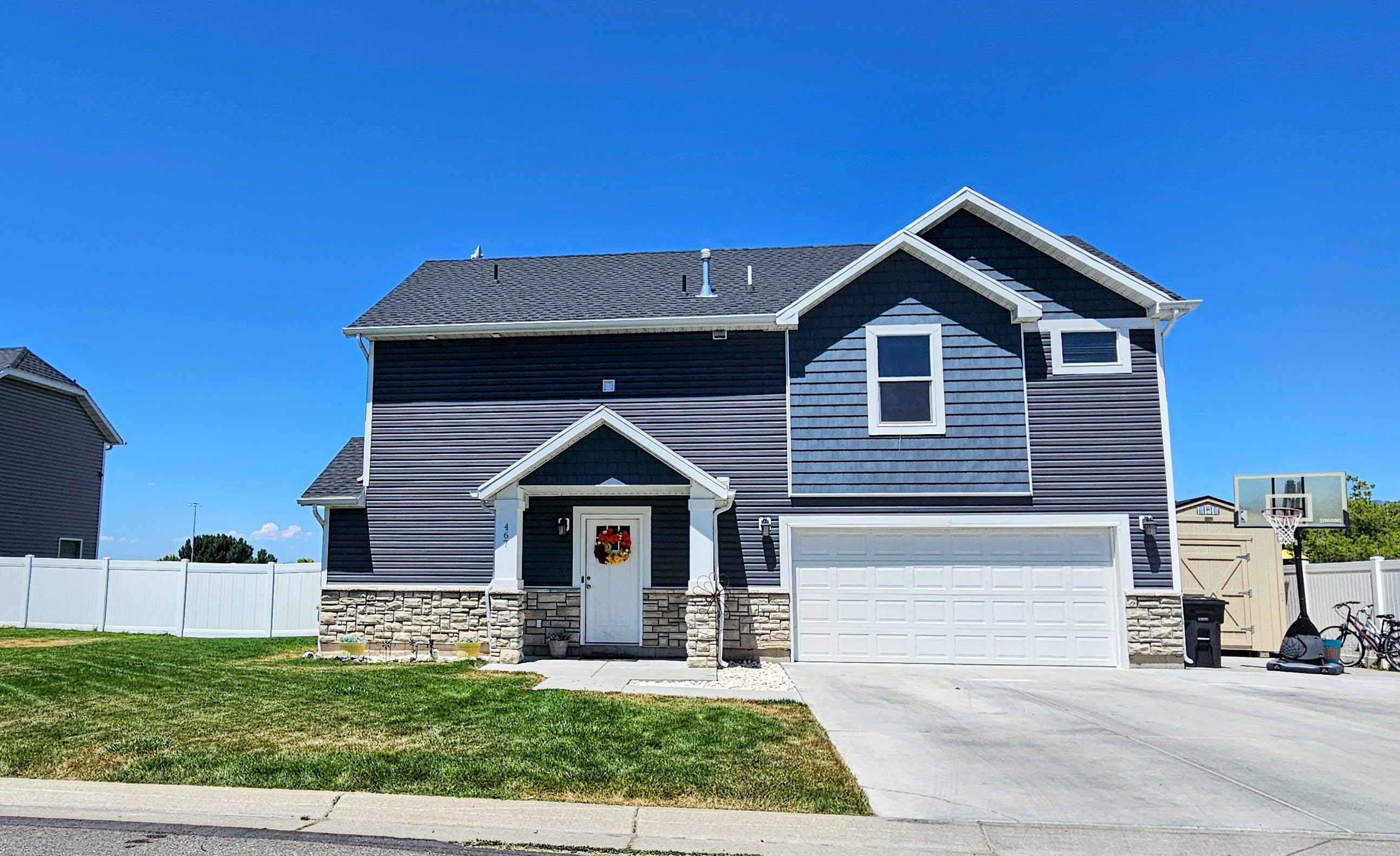 Two-story residence featuring dark blue horizontal siding, blue shingle siding, and stone veneer accents