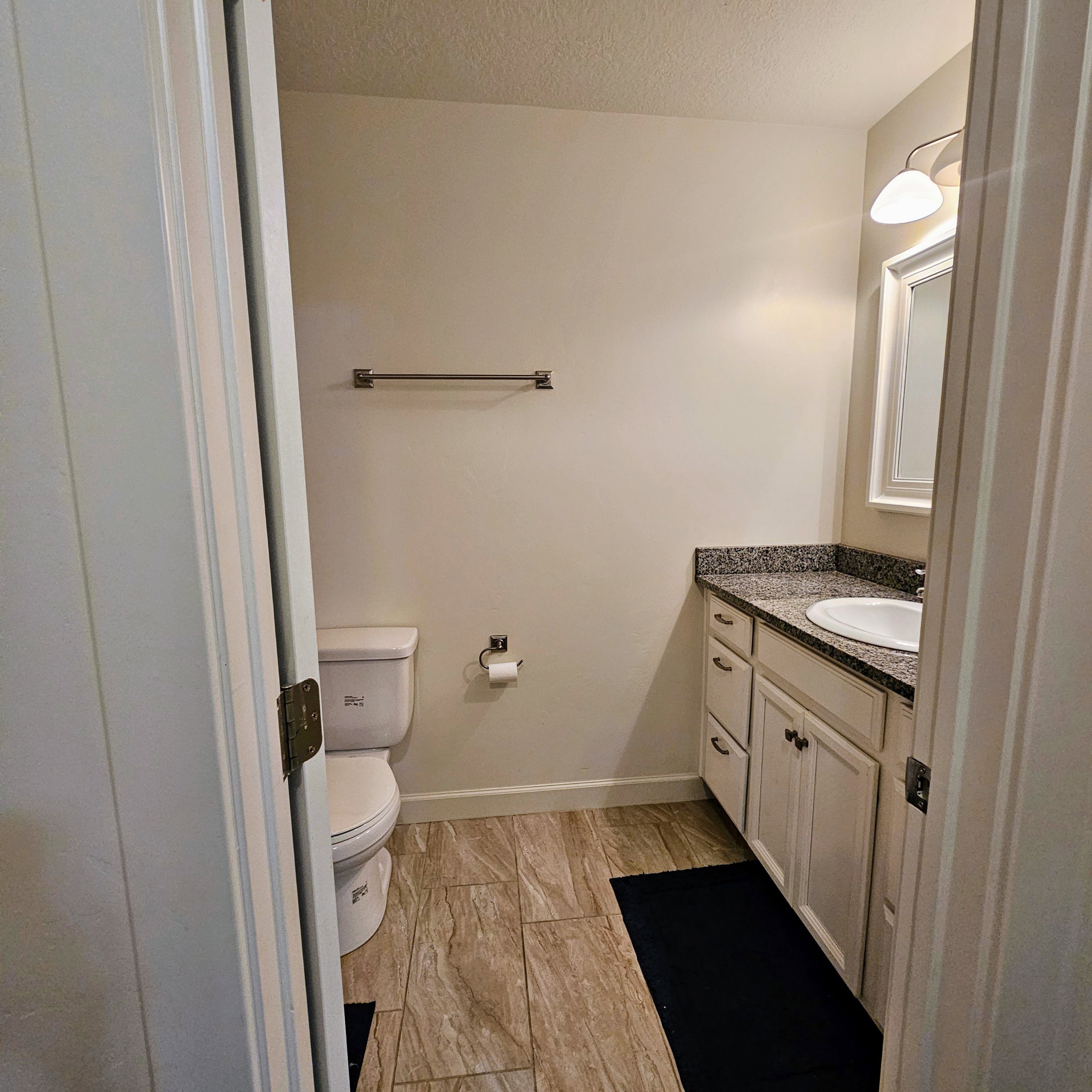 Bathroom featuring wood-finish tile flooring, a white vanity with a granite countertop, and a recessed sink