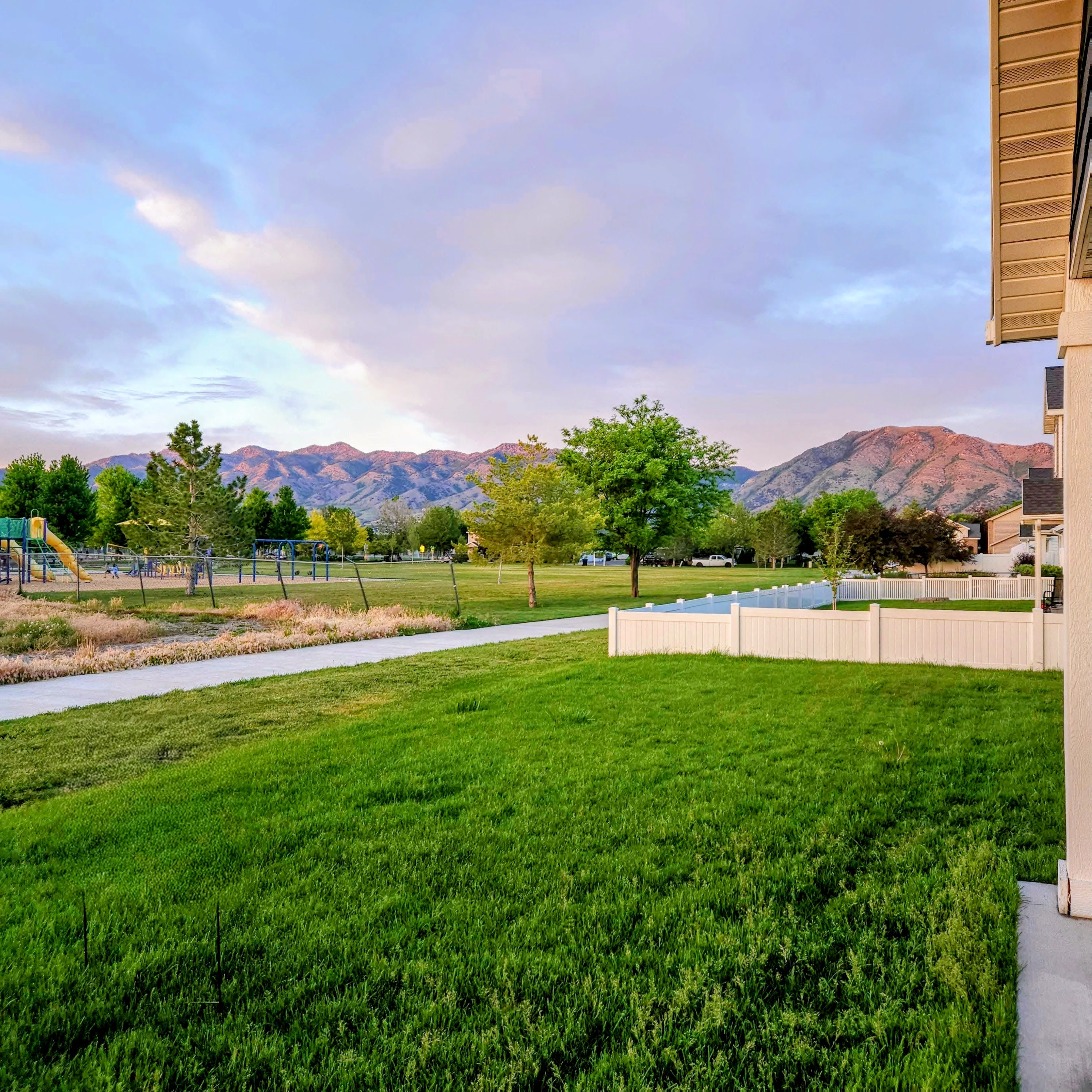 Expansive green lawn bordering a white privacy fence