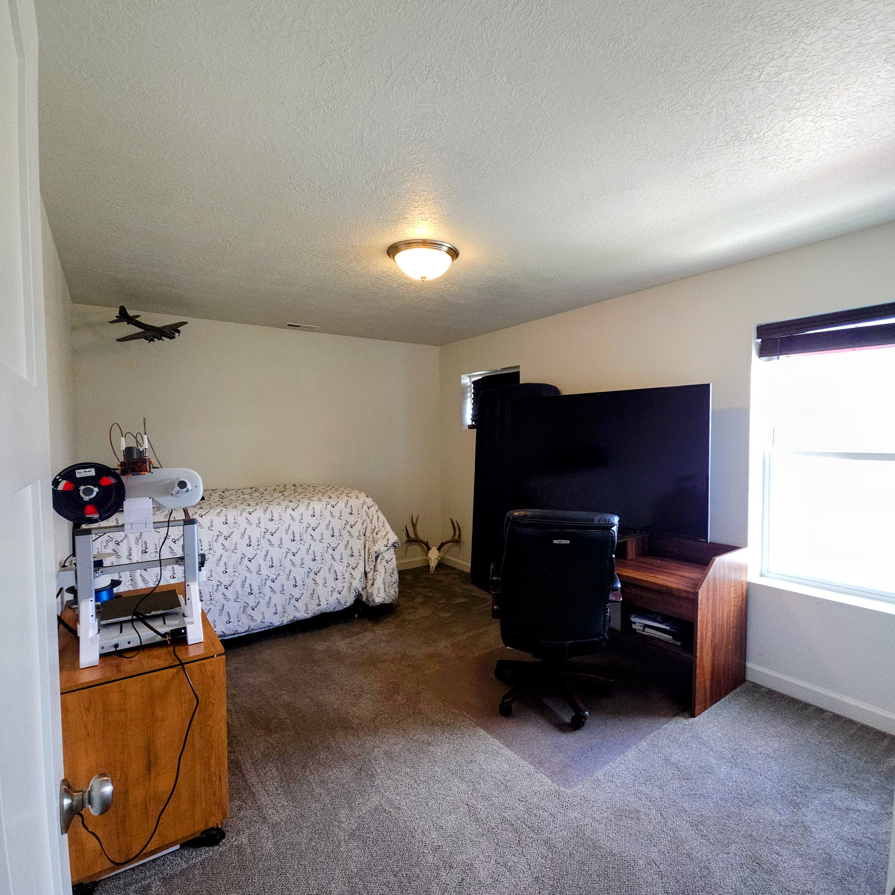 Spacious room featuring neutral carpeting, white walls, a single window with blinds, and a flush-mount ceiling light fixture