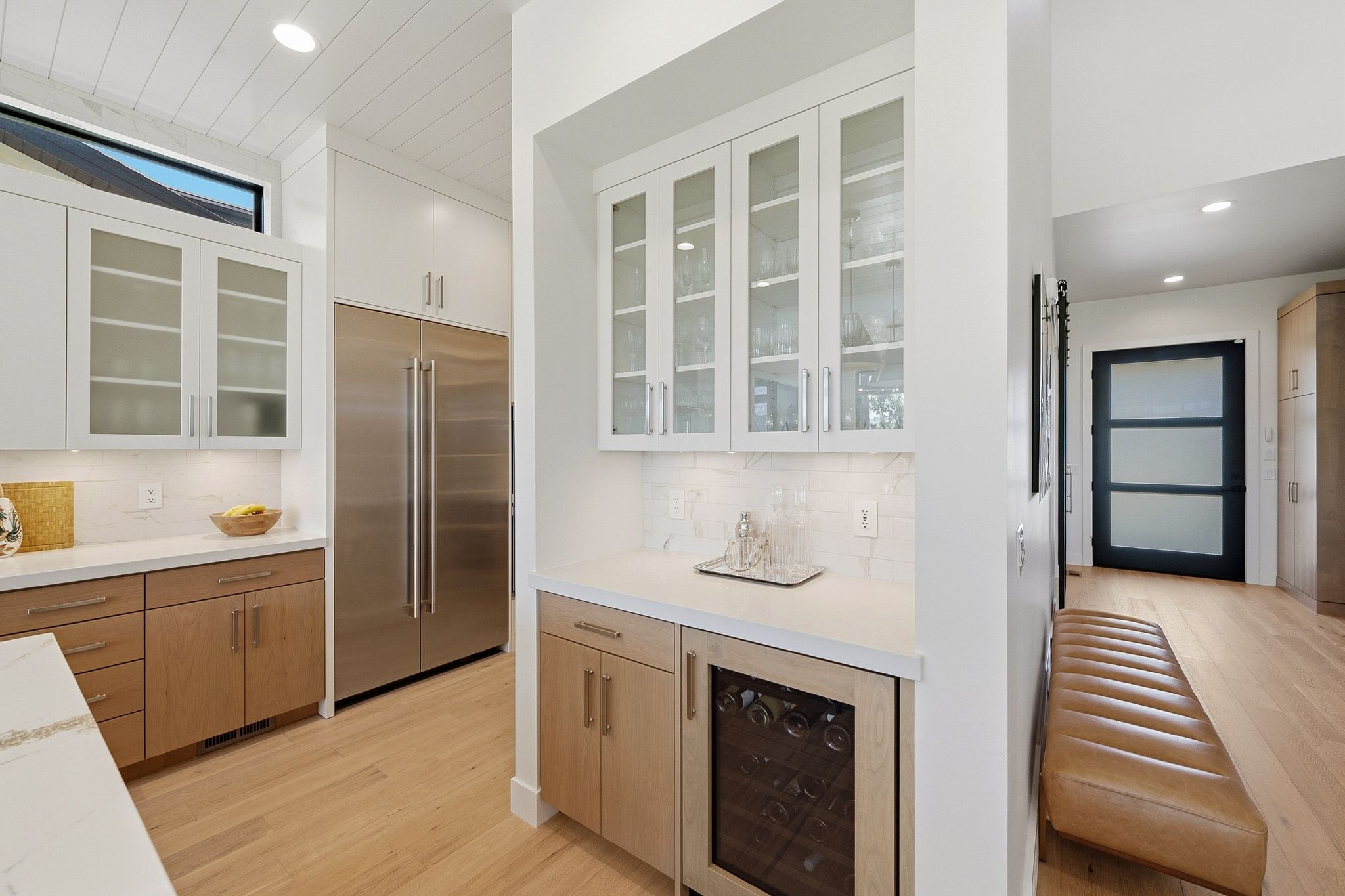 Modern kitchen featuring wood-finish flooring, white countertops, and a white subway tile backsplash