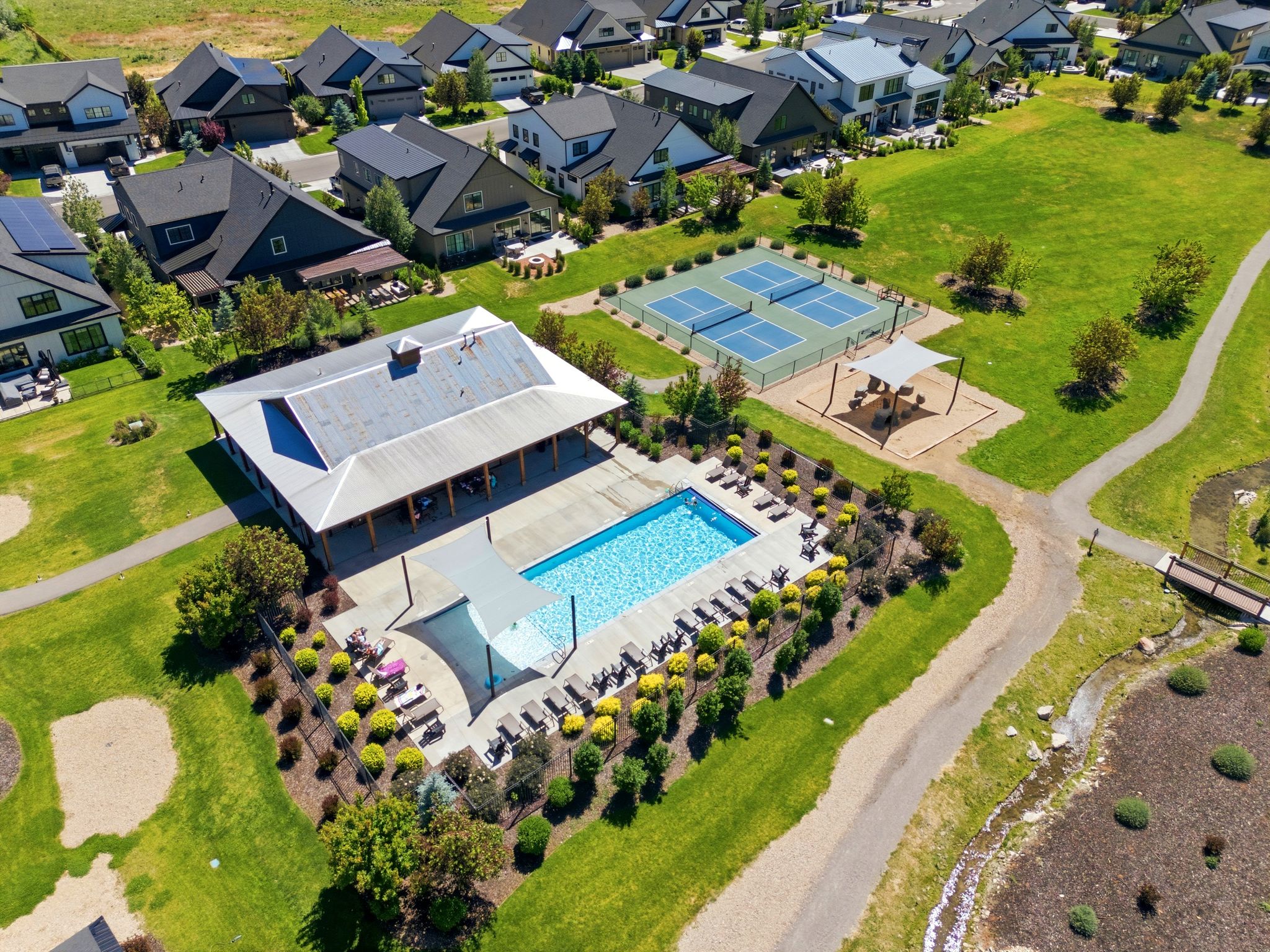 Community amenity center featuring a rectangular swimming pool, an expansive covered patio, and multiple sun-shaded lounge areas