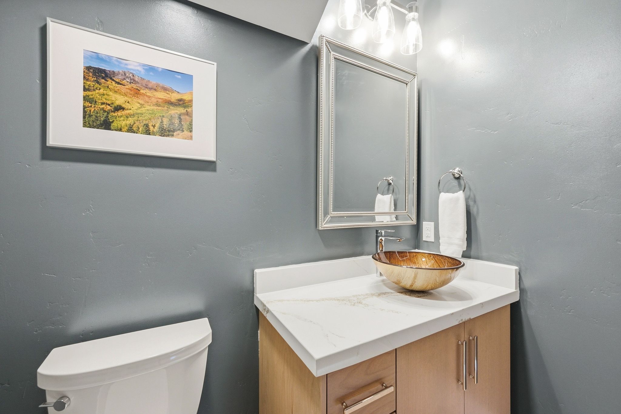 Vanity with a vessel sink, a light wood-finish base, and a light-toned countertop