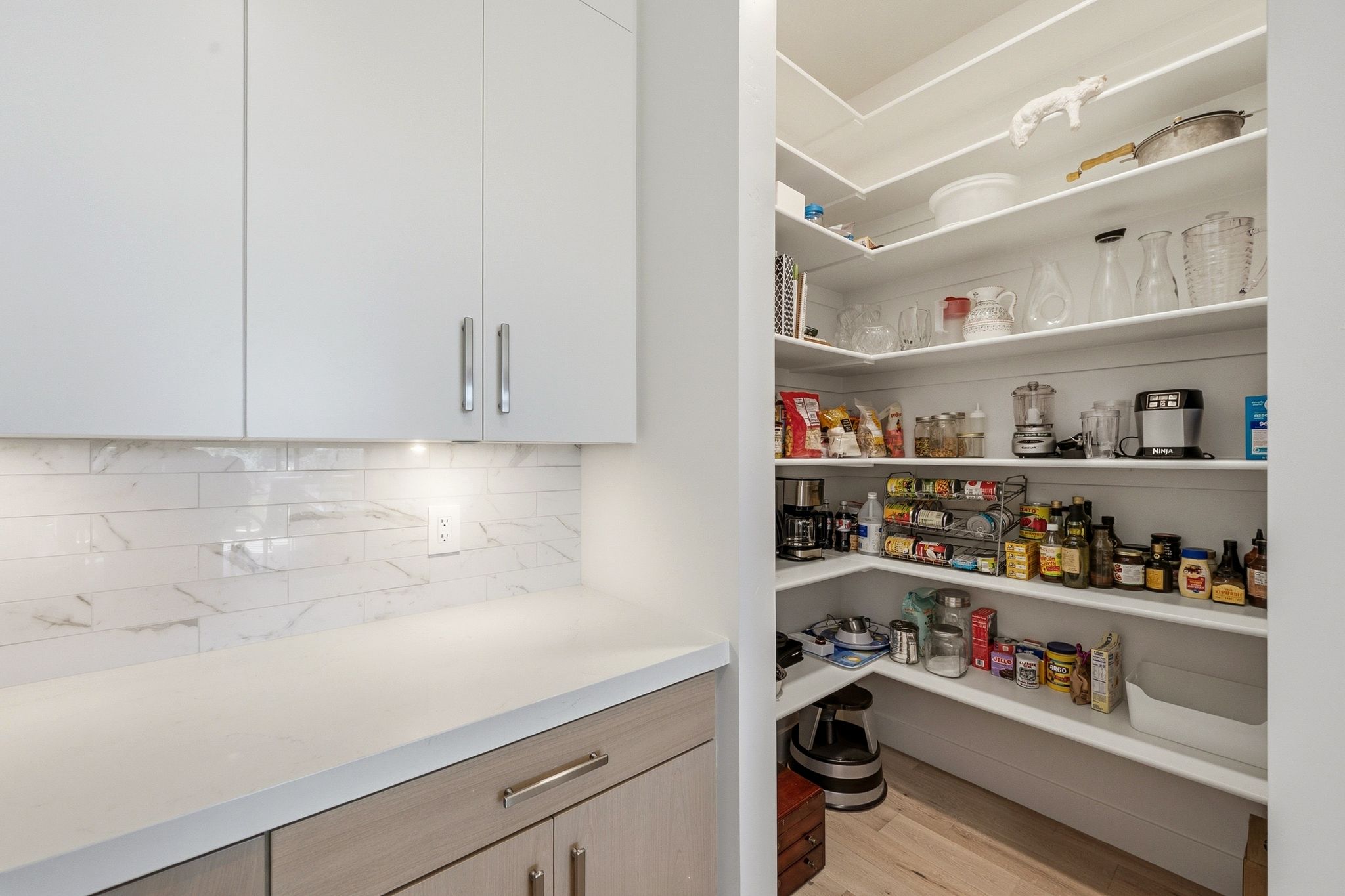 Well-appointed kitchen pantry with extensive white shelving for organized storage