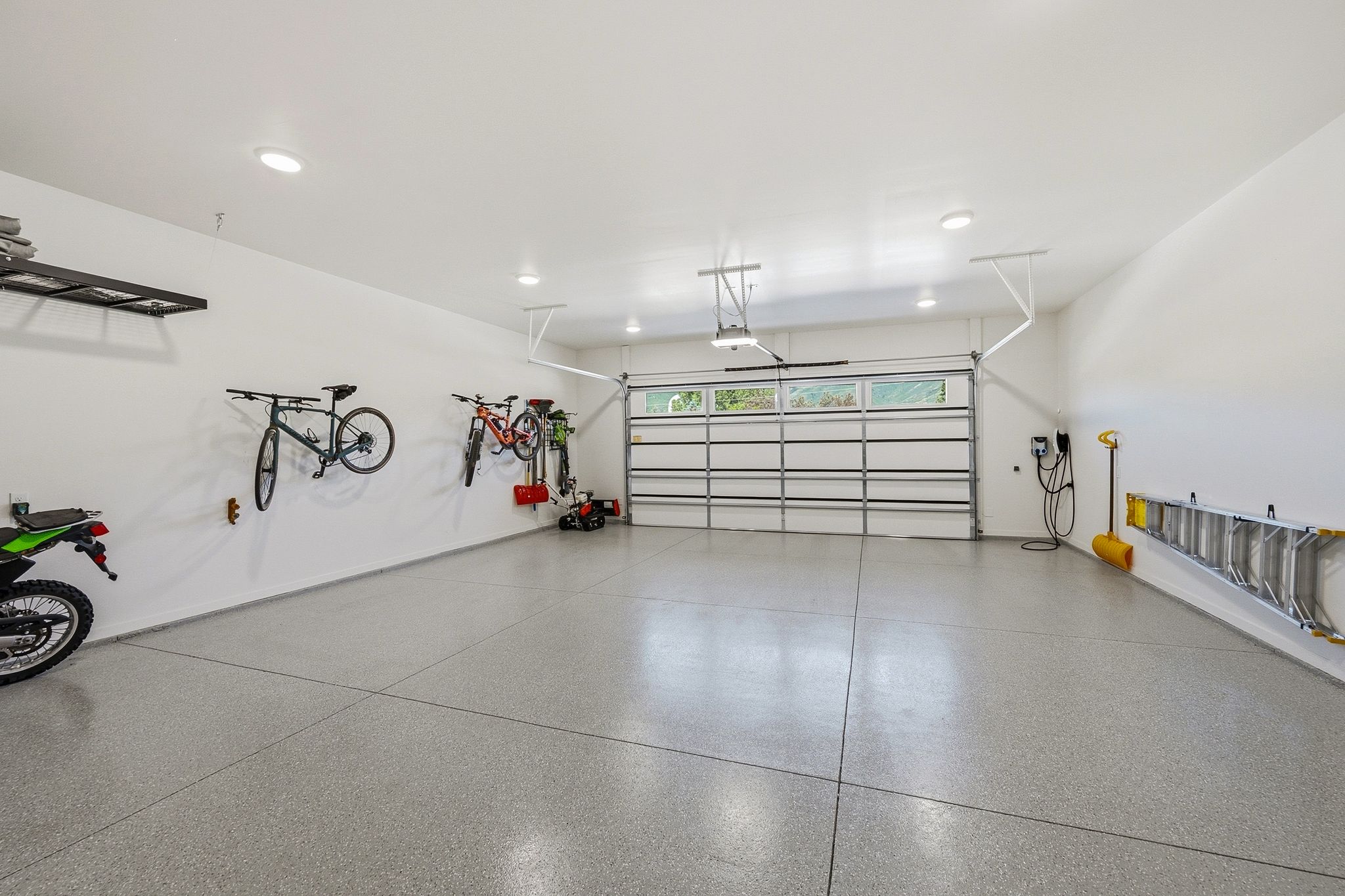 Spacious garage featuring a durable epoxy floor, recessed lighting, white walls, and an overhead door with window panels