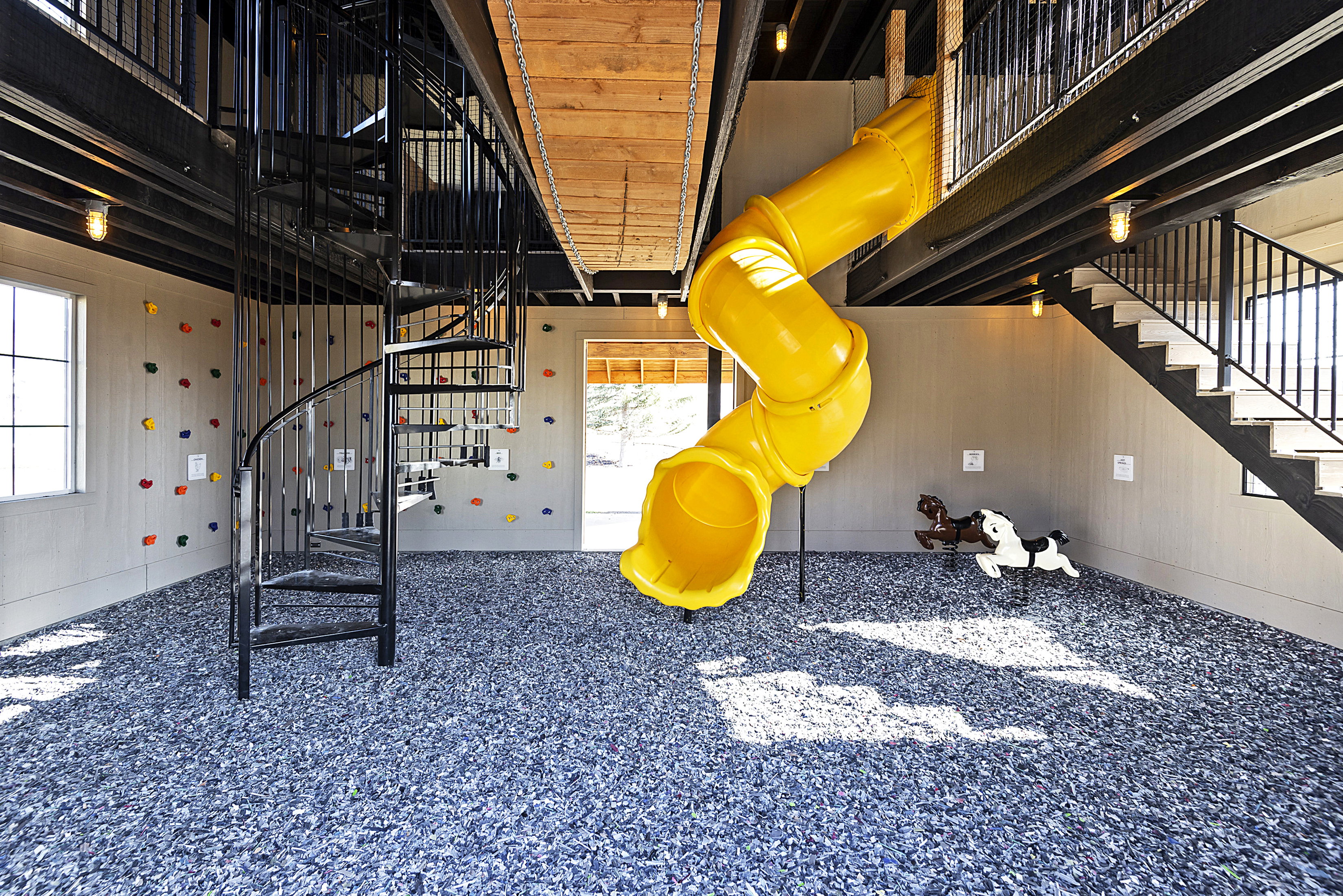 Recreational room featuring a spiral staircase, climbing wall, and a yellow tube slide