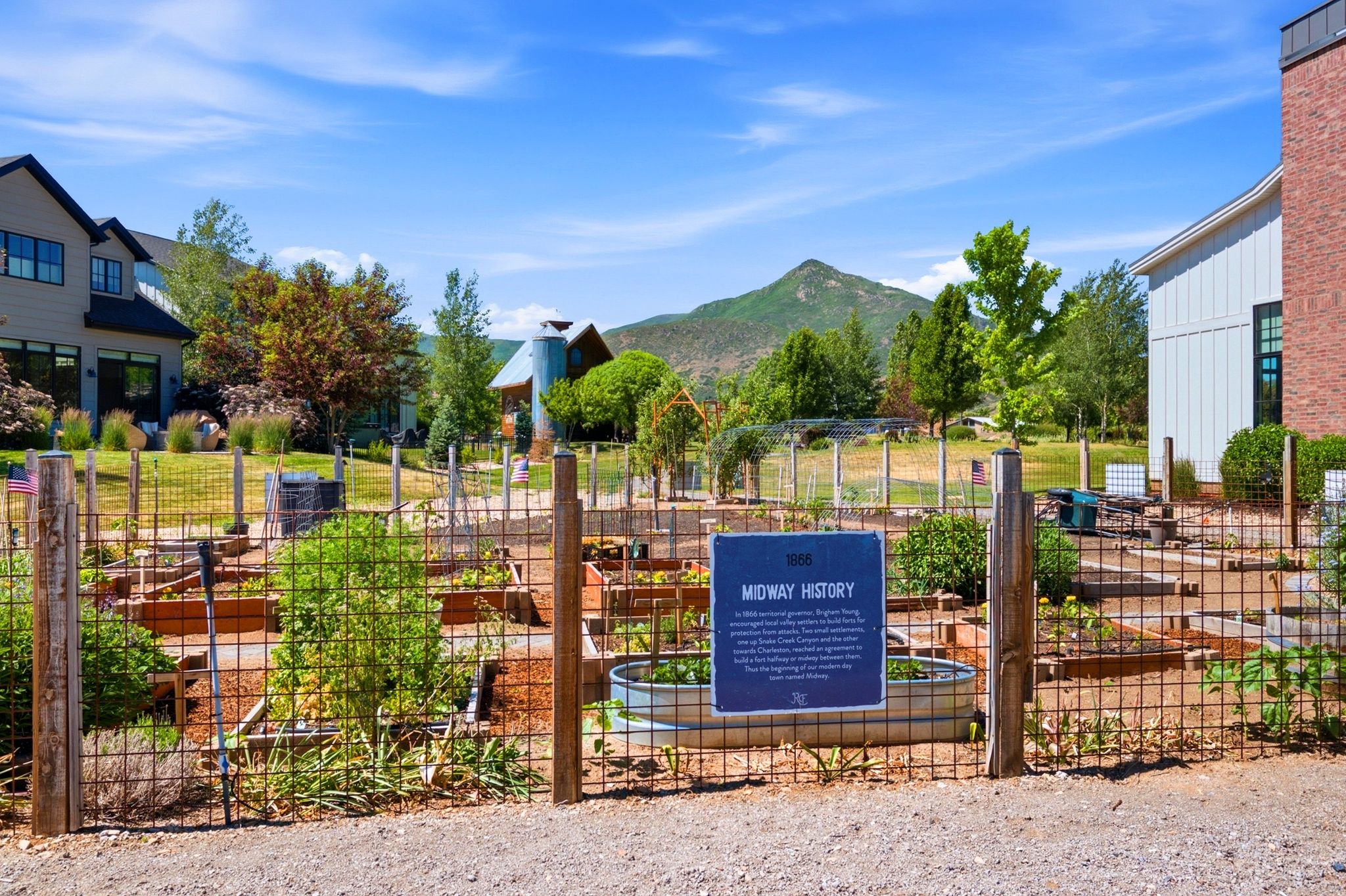 Community garden plots framed by a rustic wire fence and wood posts