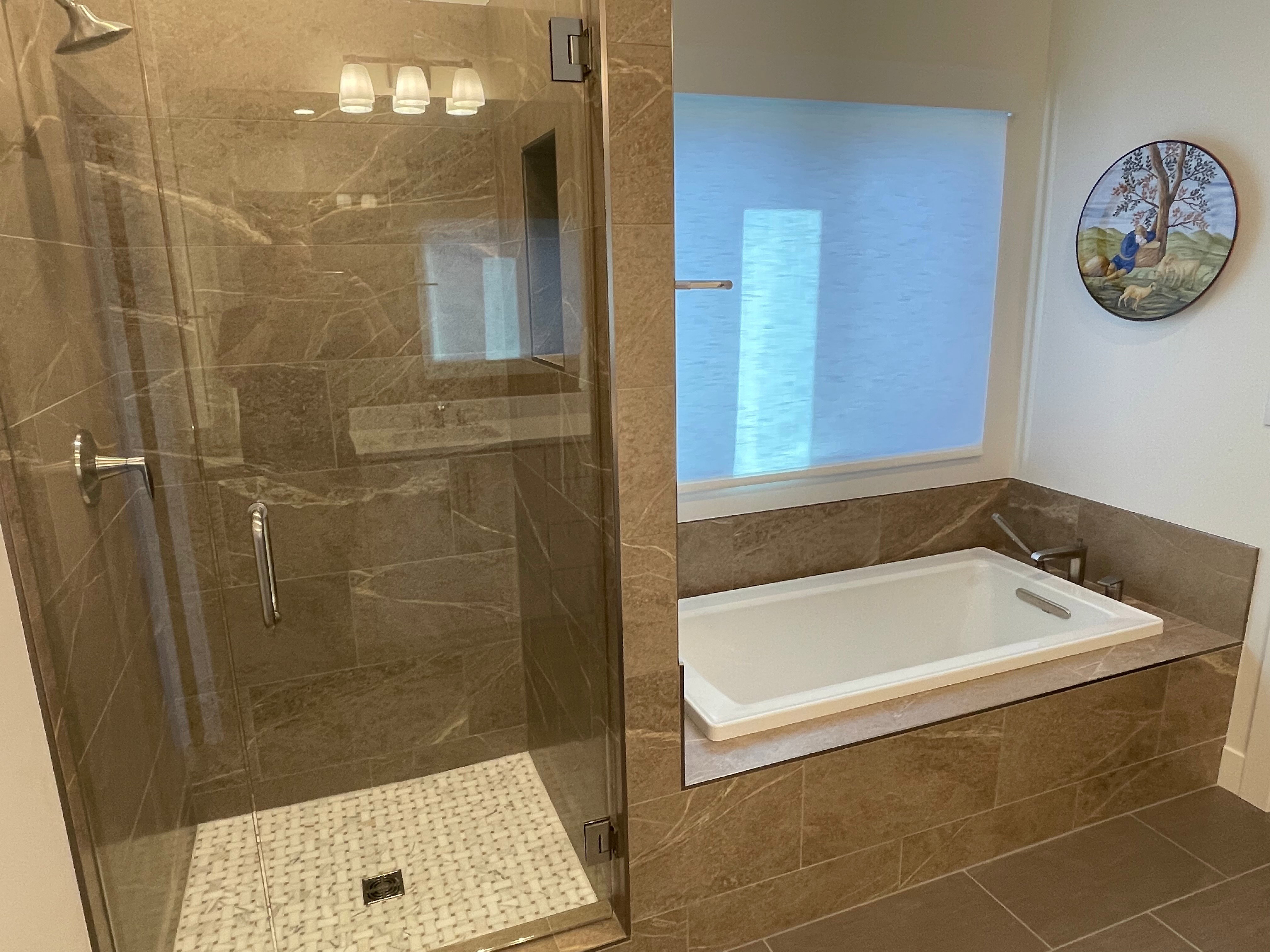 Bathroom featuring a glass-enclosed shower with stone-look tile, a built-in tub with stone-look surround, and a chrome showerhead with matching fixtures