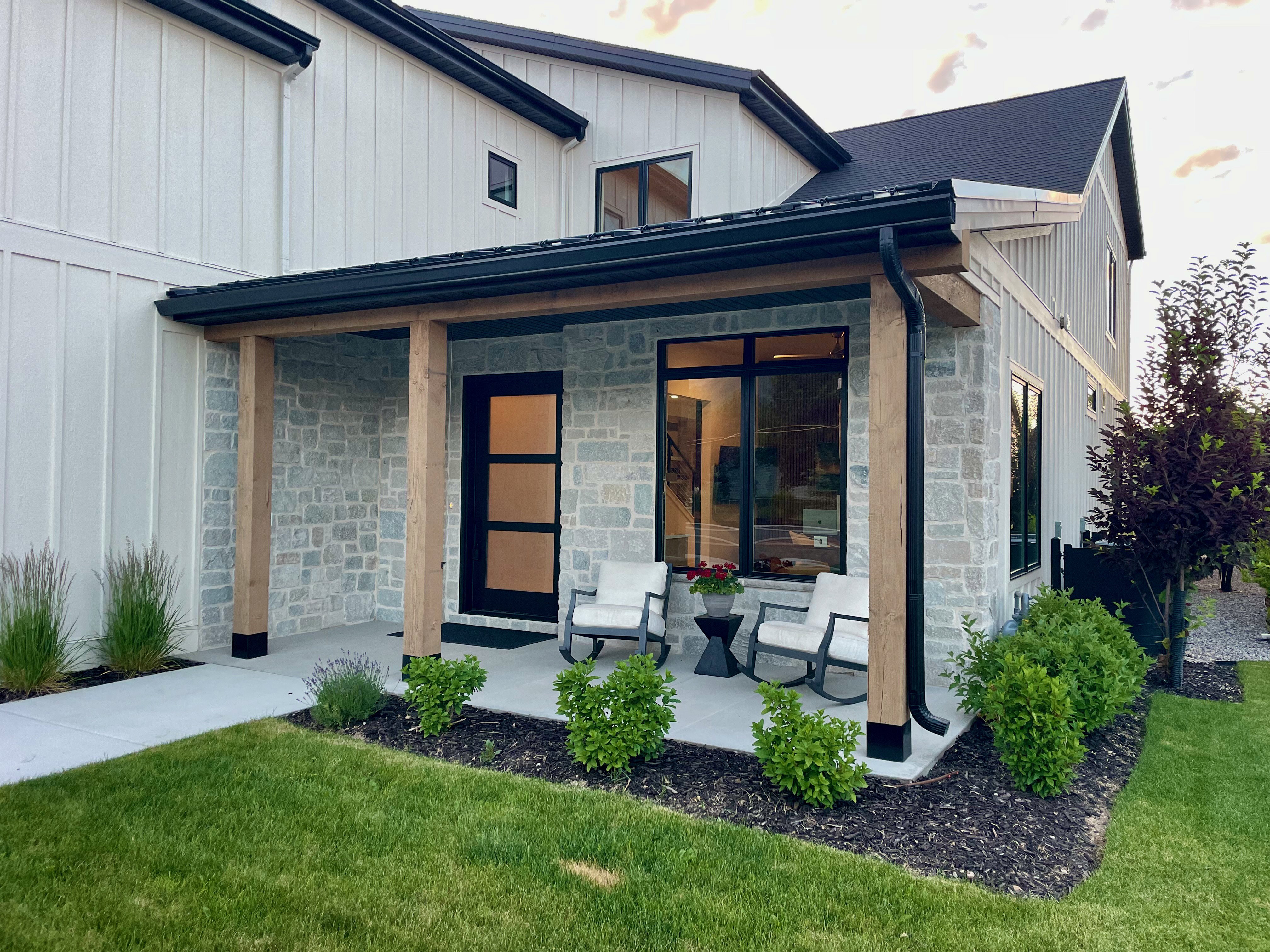 Modern farmhouse exterior featuring board and batten siding, light-colored stone accents, and a covered porch