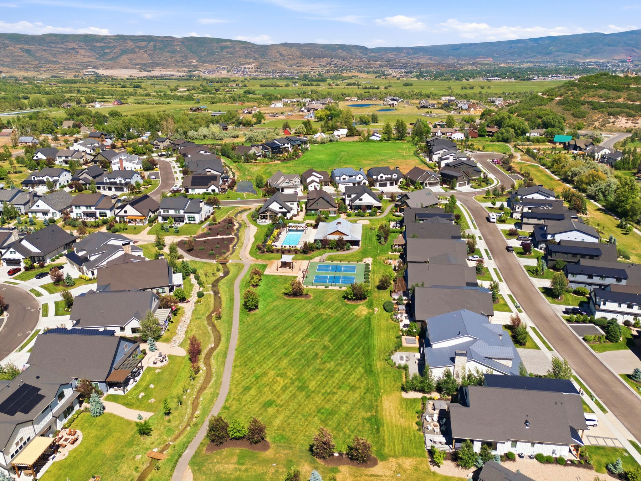 Aerial representation of a residential community featuring diverse architectural styles, an outdoor swimming pool, and multiple tennis courts