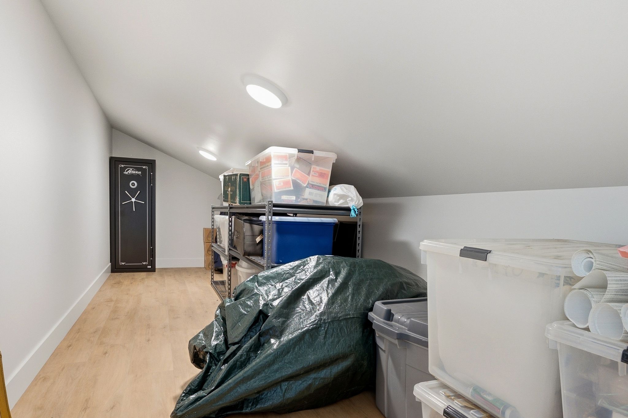 Attic storage space featuring wood-finish flooring, white walls, and recessed ceiling lighting
