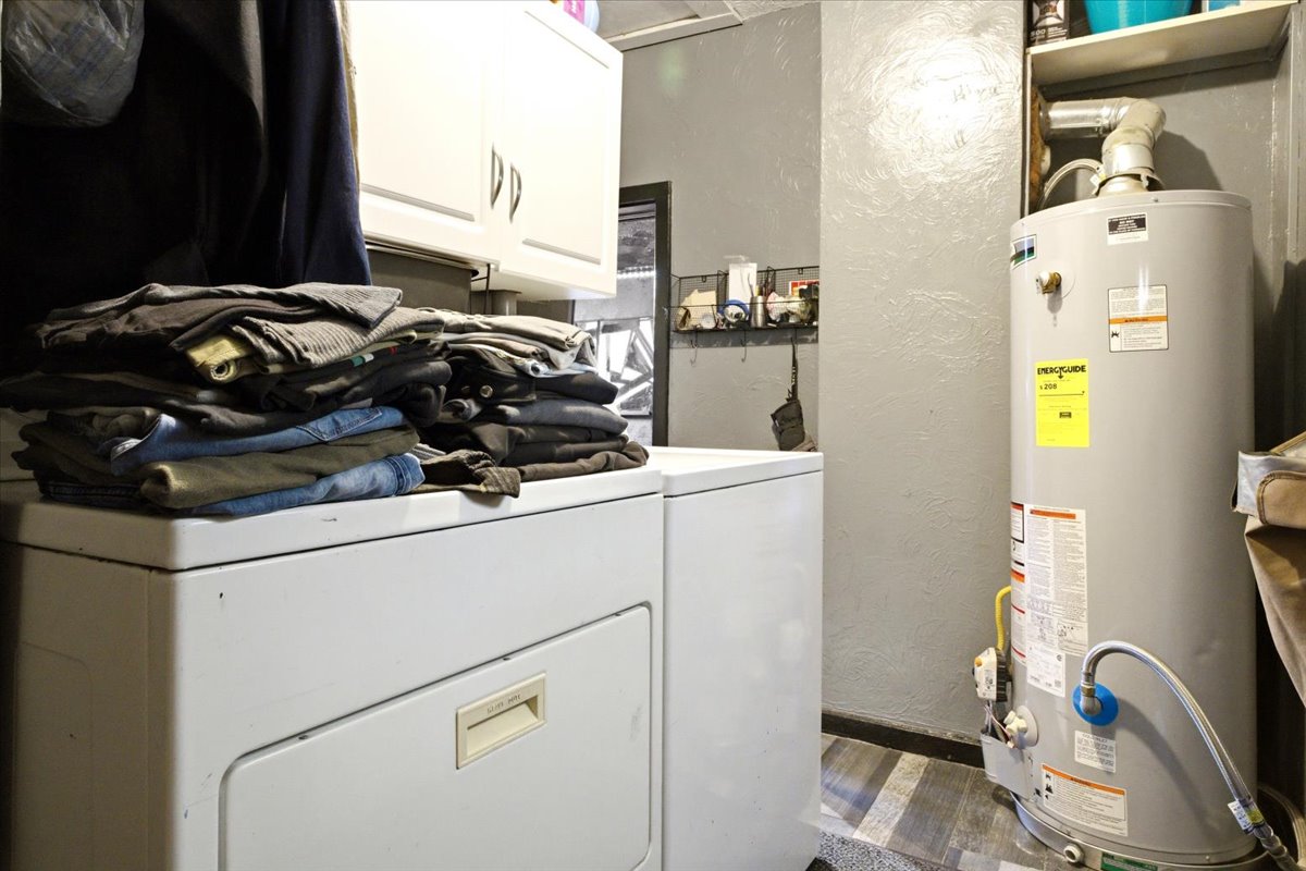 Laundry area featuring a water heater, upper cabinetry, and wood-finish flooring