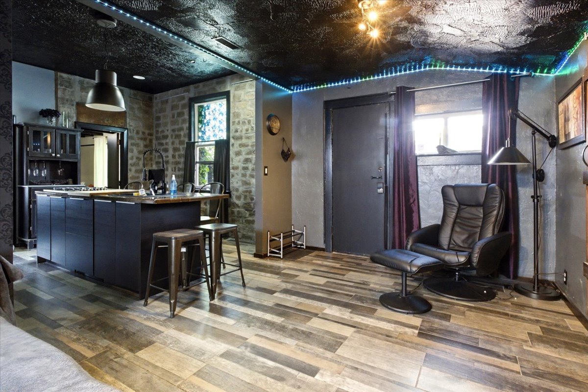 Open-concept living space featuring wood-finish flooring and exposed stone walls